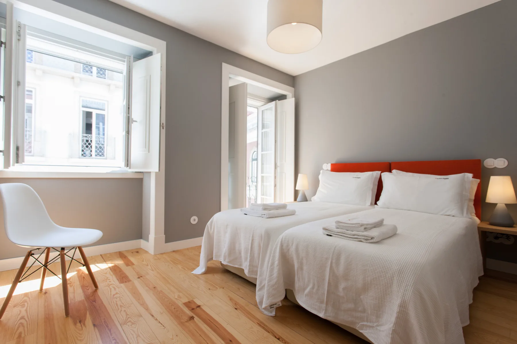 Un dormitorio luminoso con una cama bien hecha y ventanas grandes.