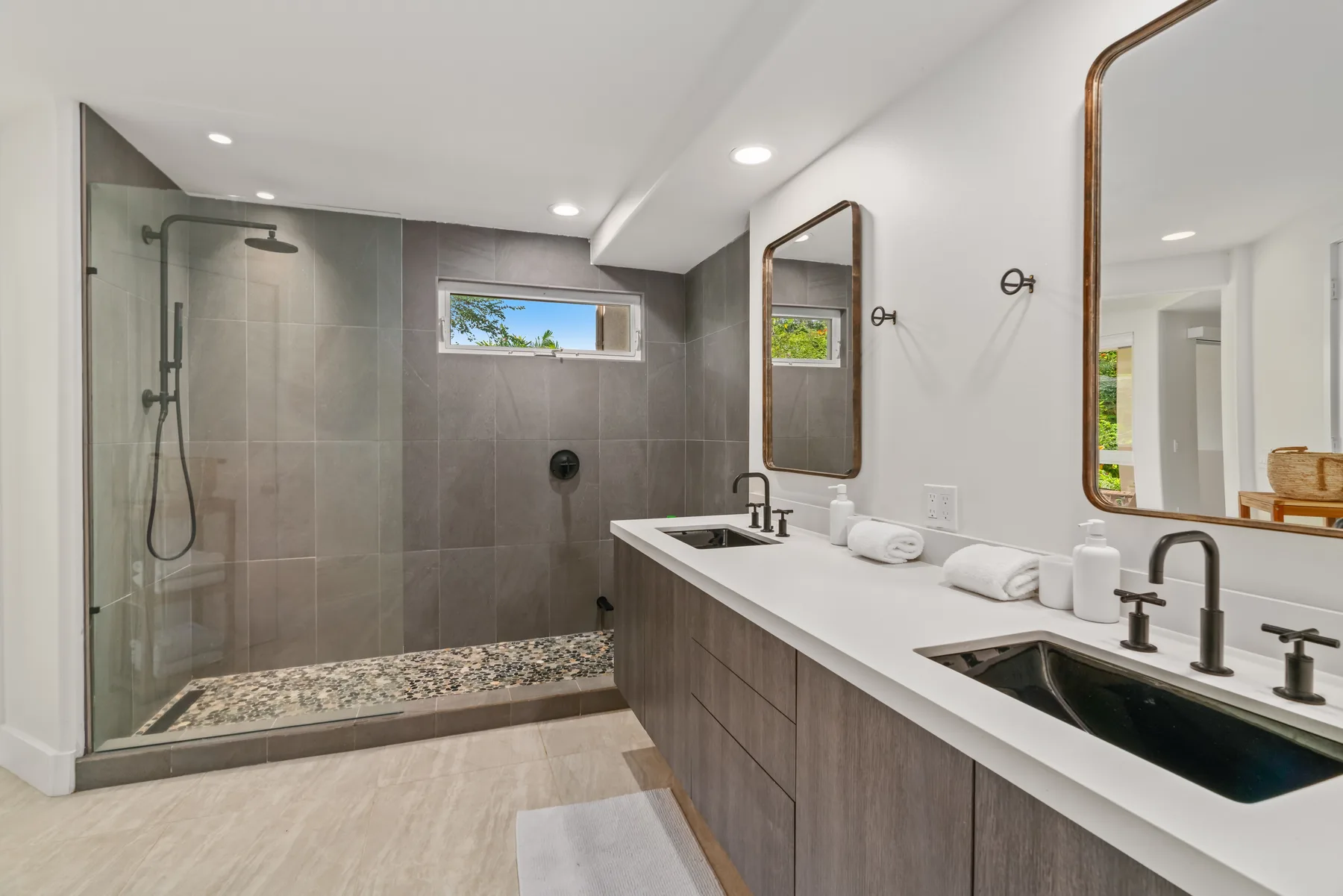 A modern bathroom with a glass shower and a long double-sink vanity.