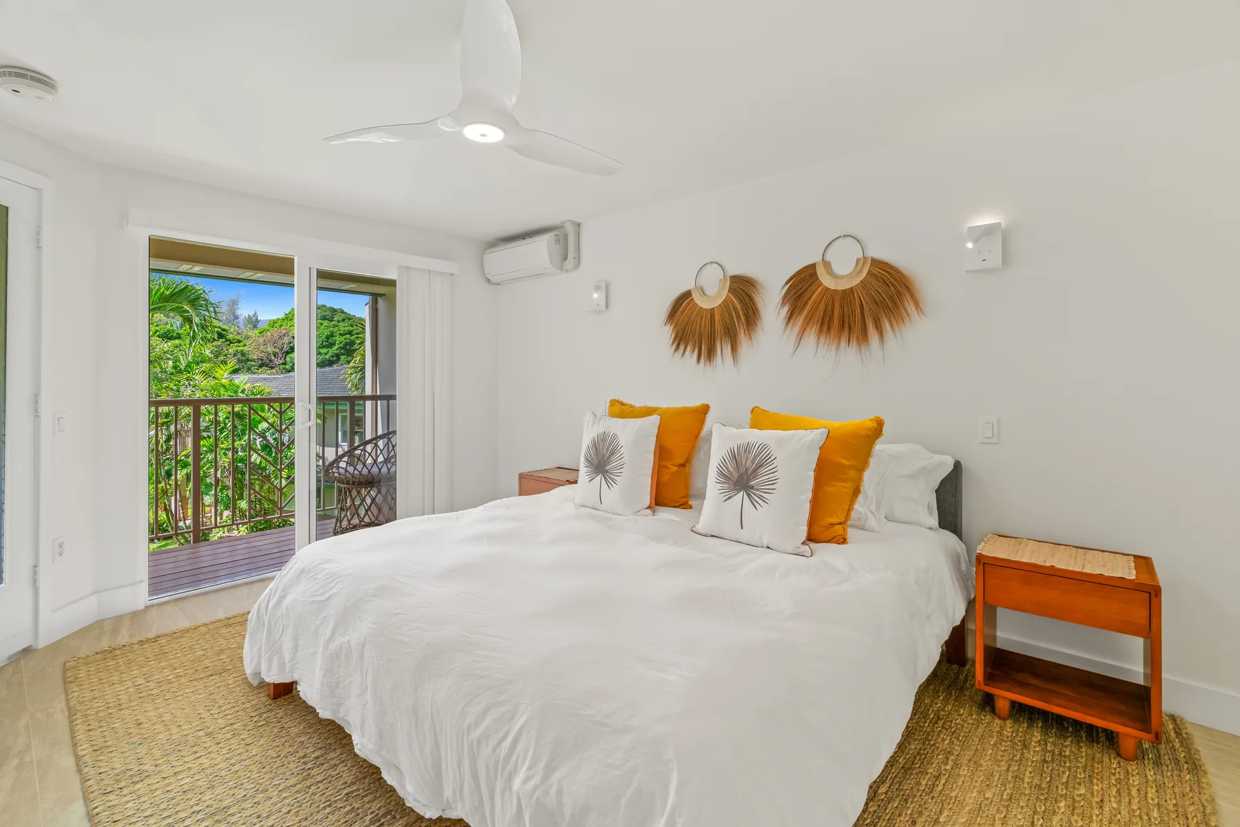 A bright bedroom with a white bed and glass doors opening to a balcony.