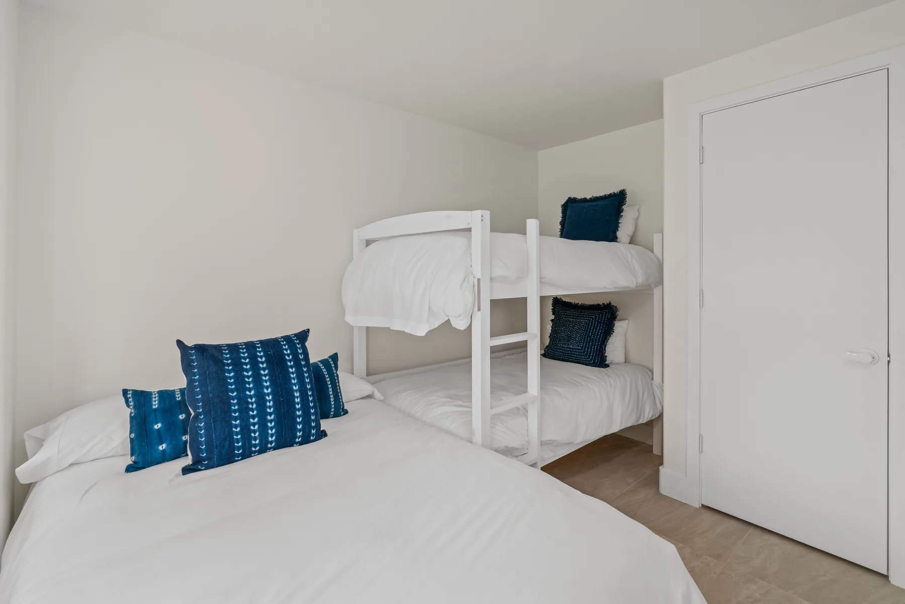 A bedroom with a bed in the foreground and bunk beds against the wall.