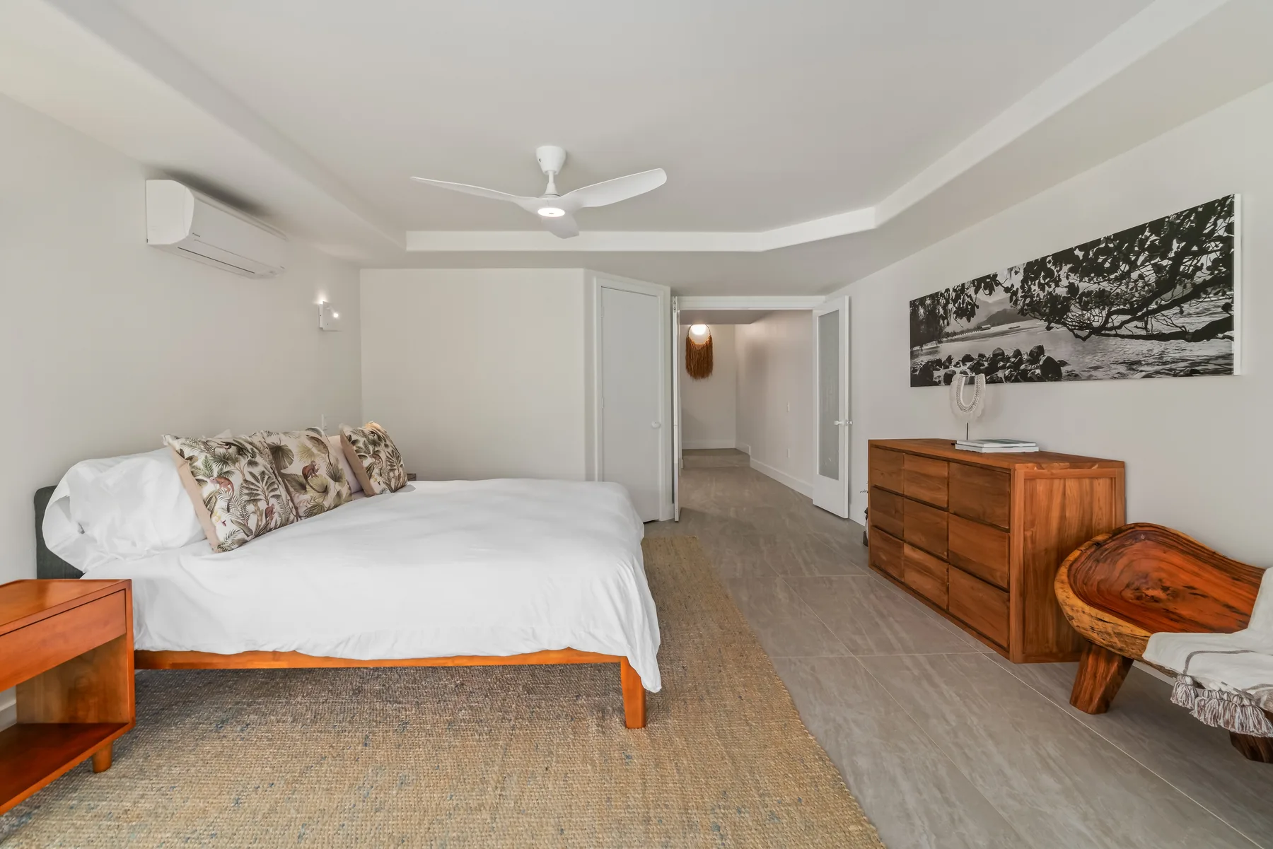 A bedroom with a bed, wooden dressers, and an open doorway.