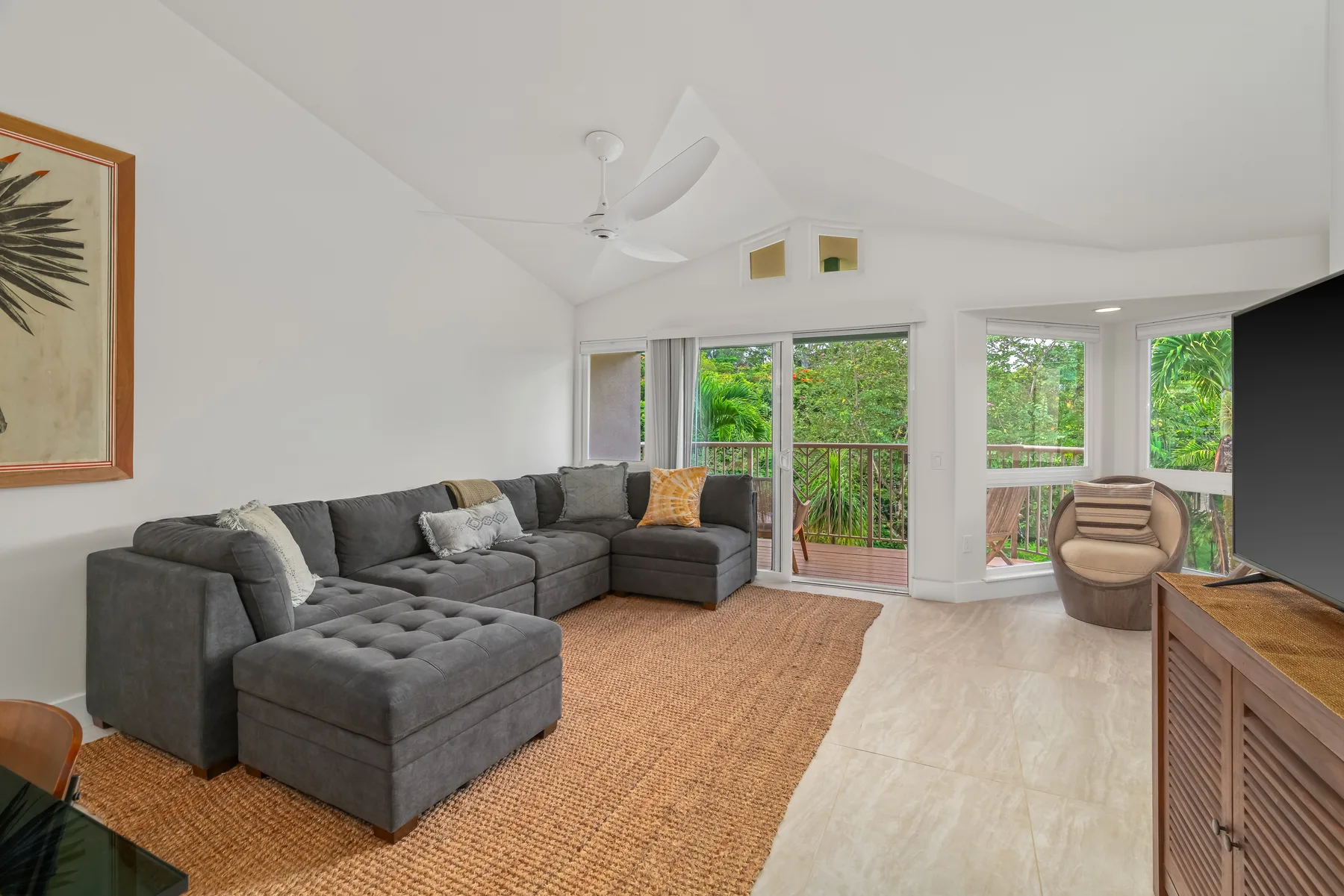 A living room with sectional seating and large windows overlooking greenery.