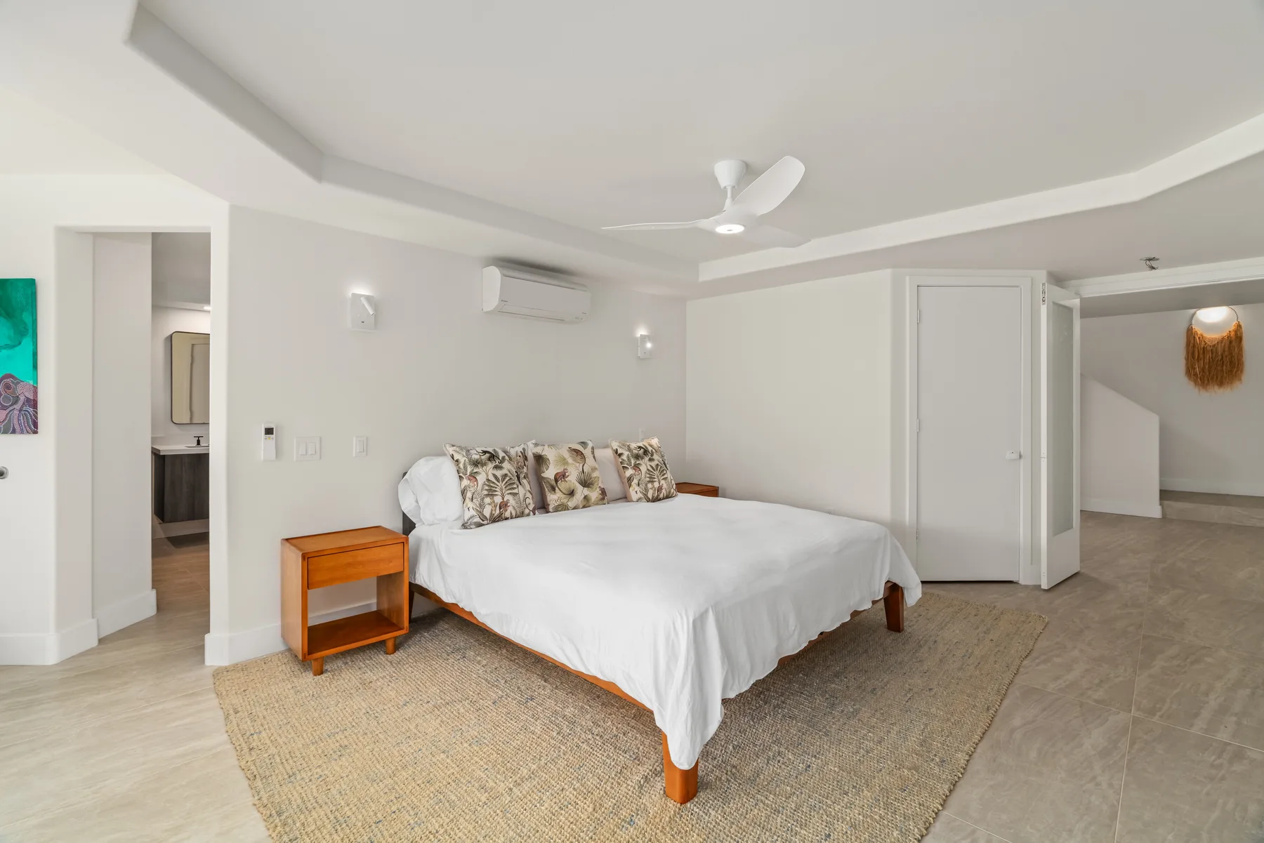 A bright bedroom with a large bed and a ceiling fan.