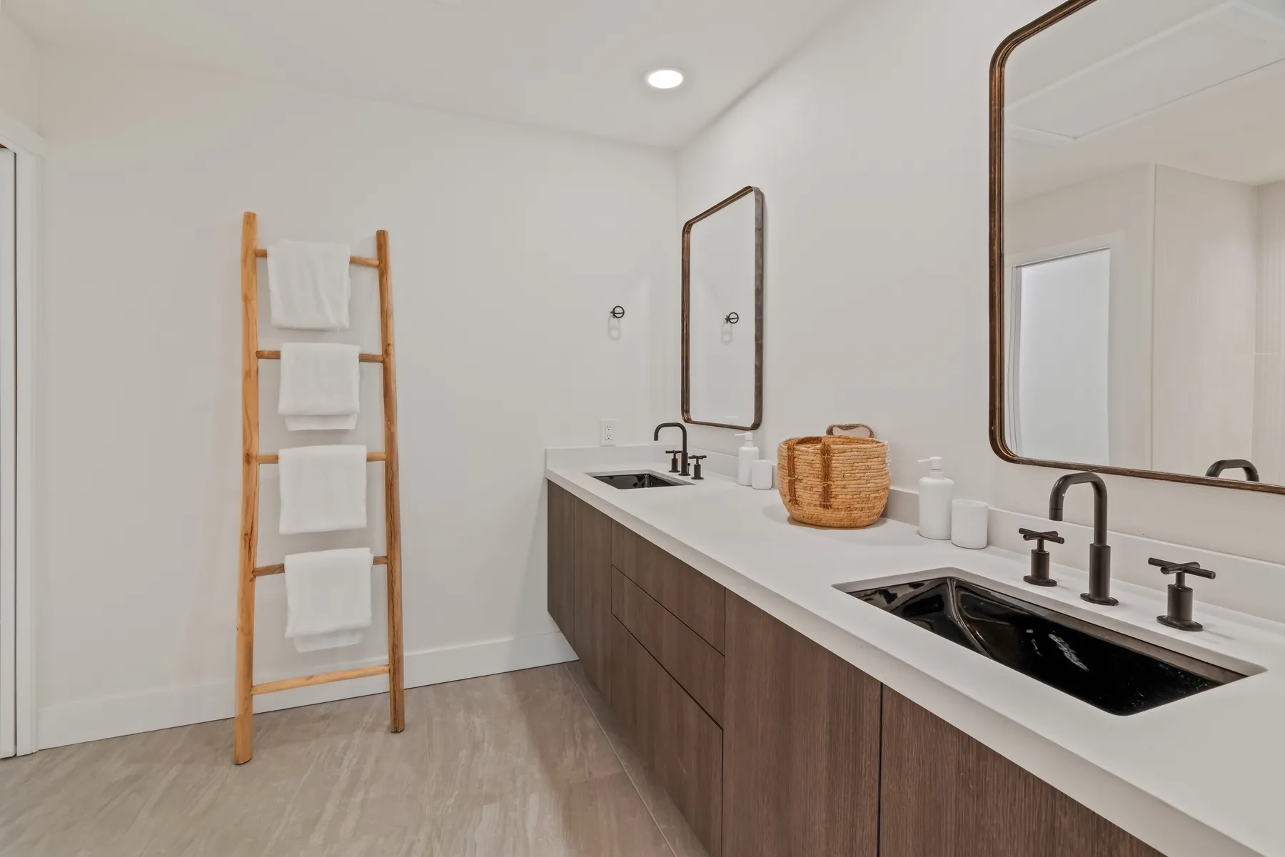A bright bathroom with a long vanity, two sinks, and wall mirrors.