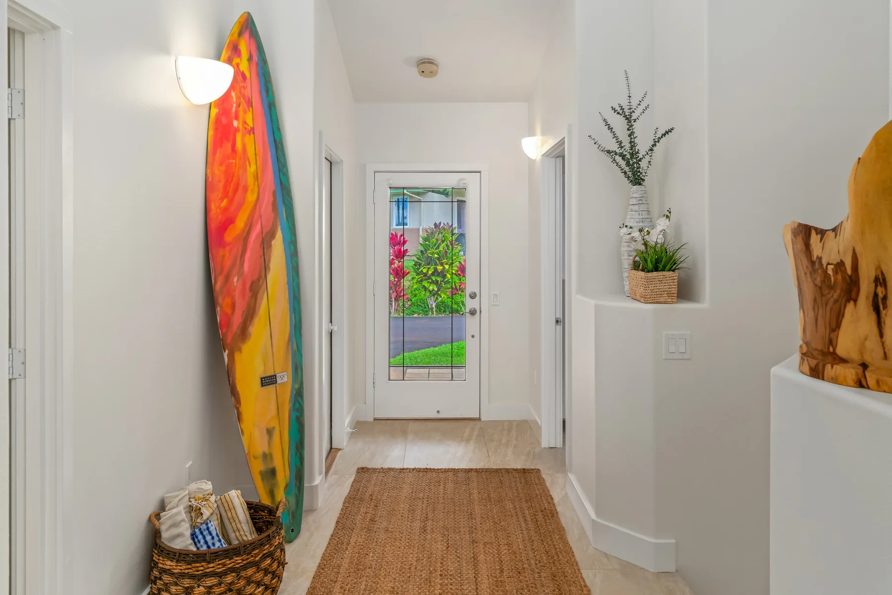 A bright hallway with colorful wall art and a glass-paneled exterior door.