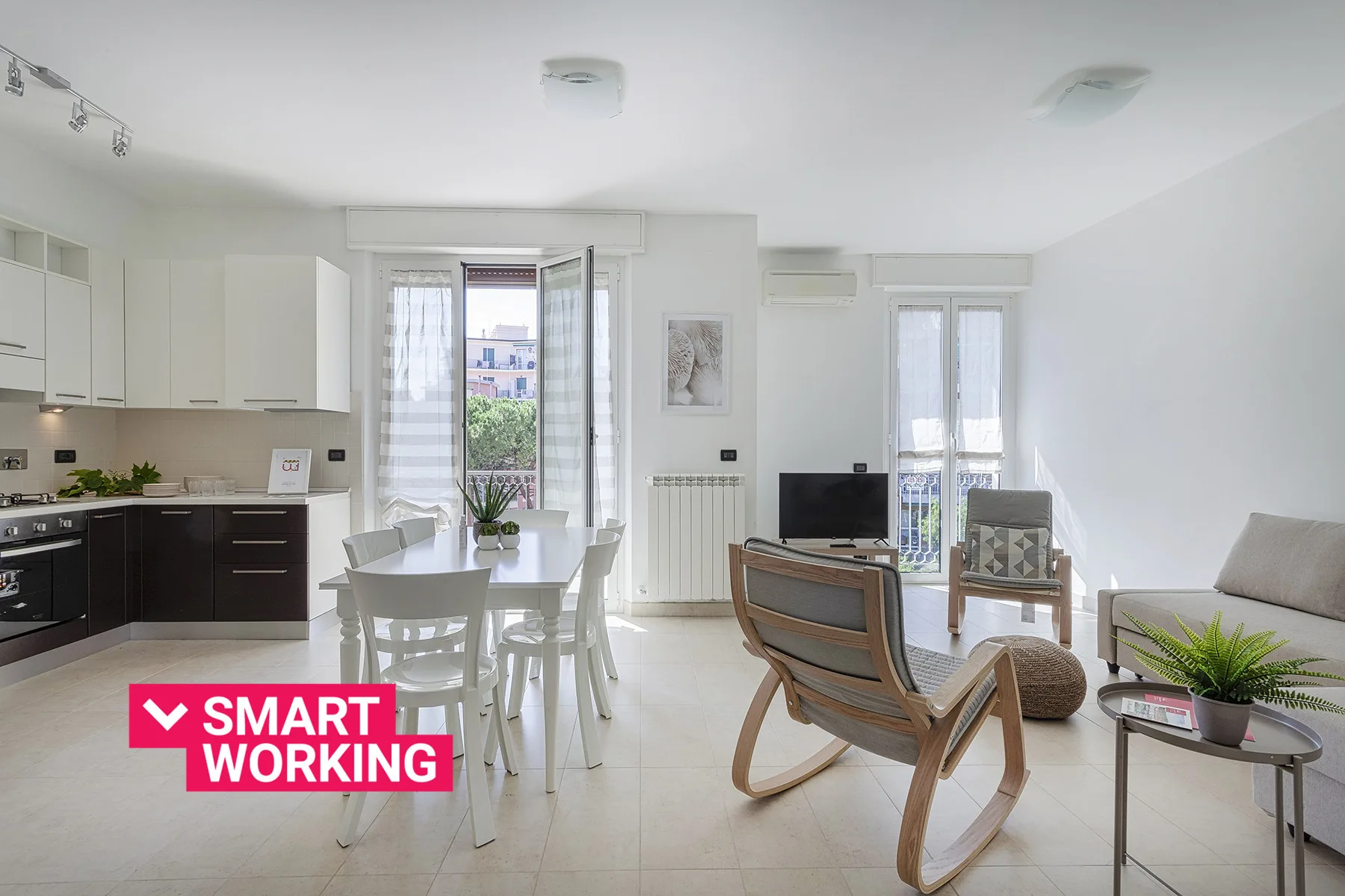 A bright open-plan living and dining area with a kitchen and balcony doors.