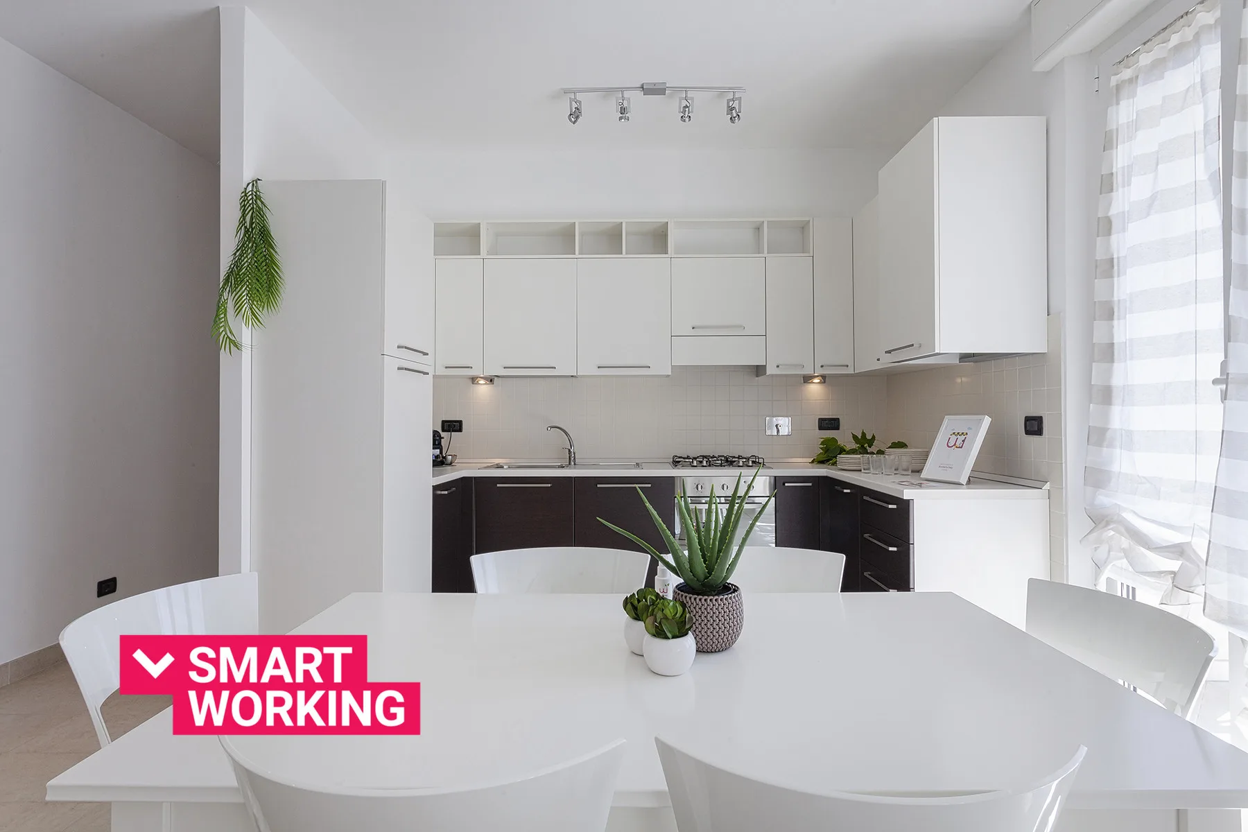 Una cocina moderna y luminosa con armarios blancos y una mesa de comedor en primer plano.