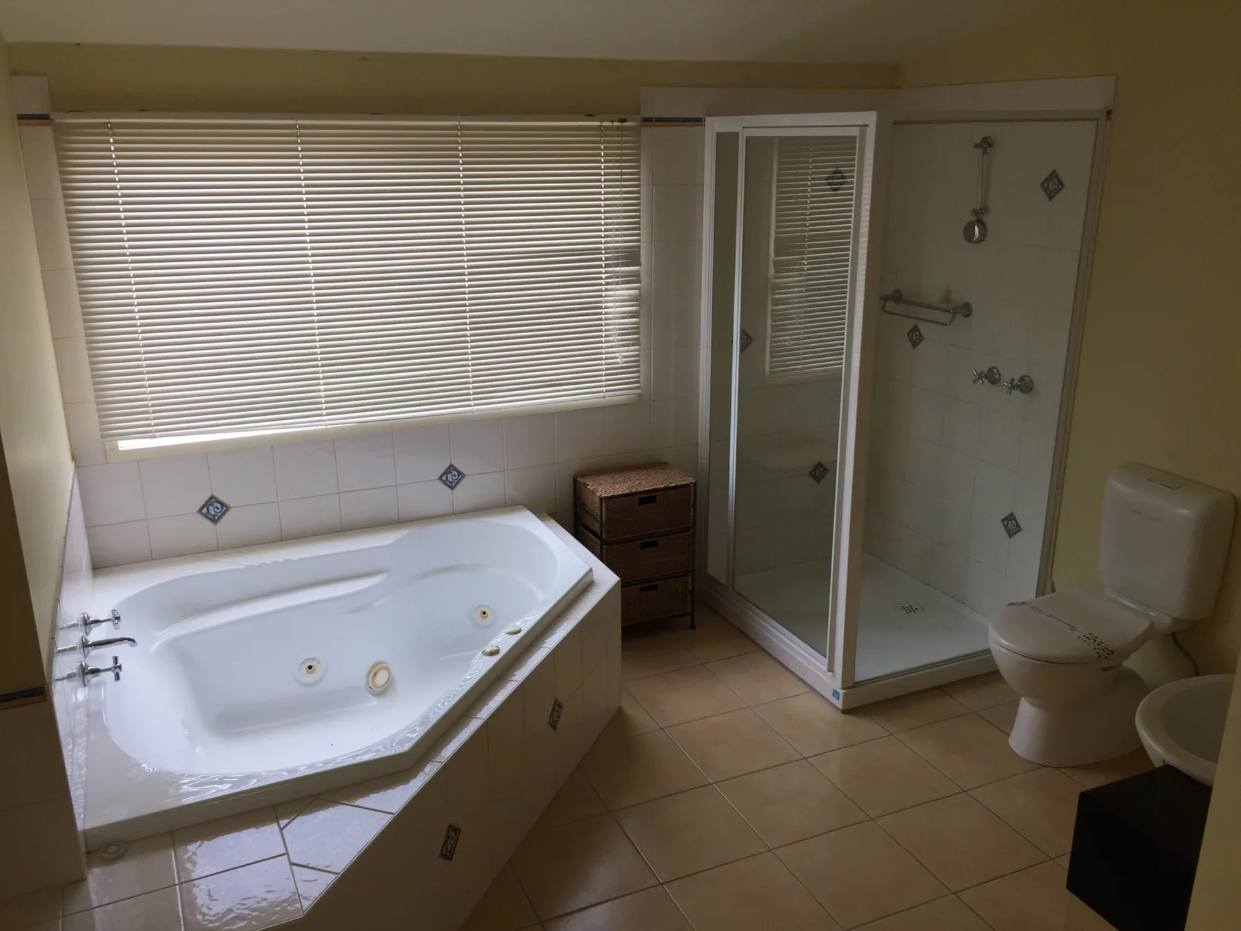 A tiled bathroom with a corner bathtub, shower, and toilet.