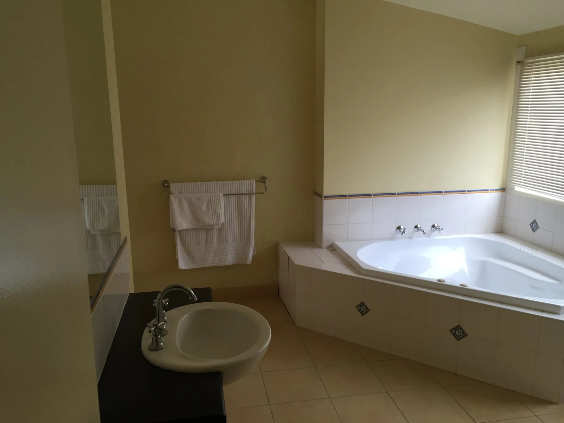 A bathroom with a sink and a built-in bathtub beneath a window.