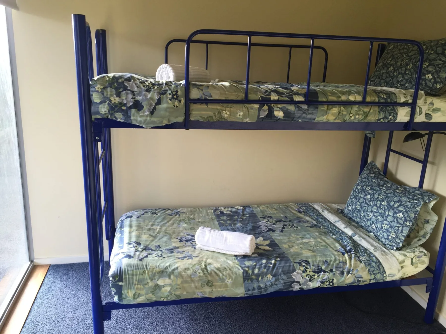 A bunk bed with patterned bedding stands against a plain wall.
