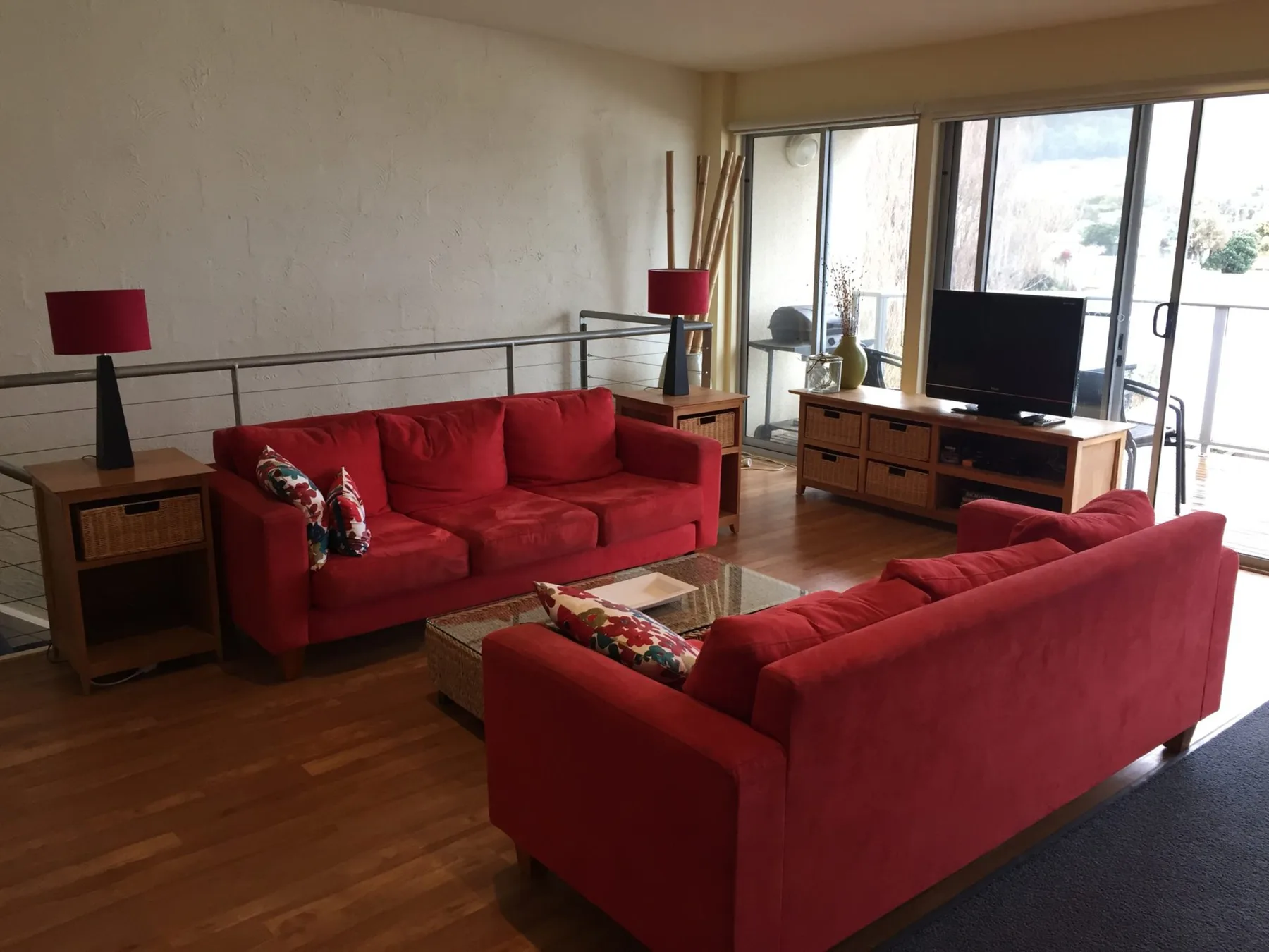 A living room with red seating, a television, and large windows.