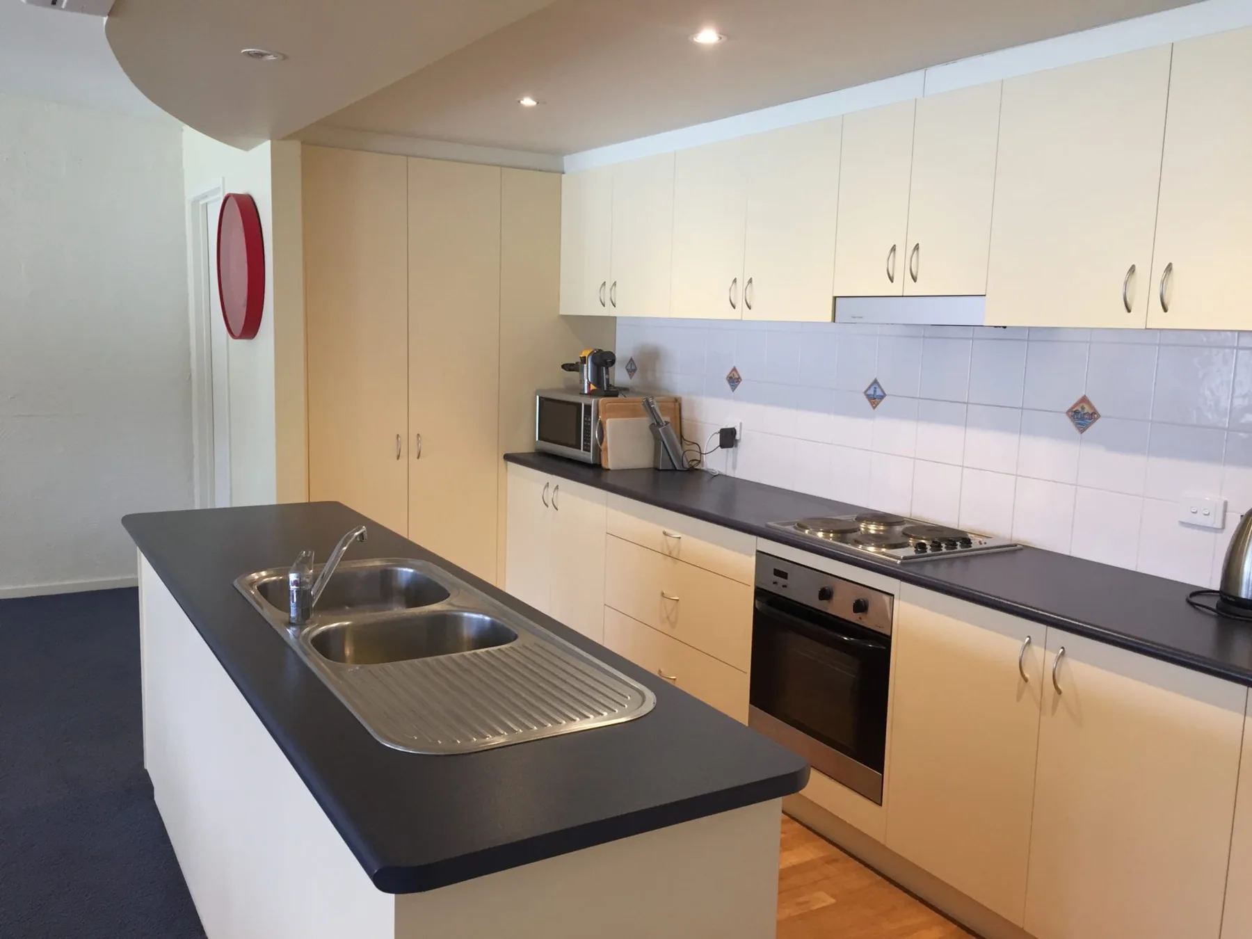 A bright kitchen with pale cabinets, dark countertops, and a central island.