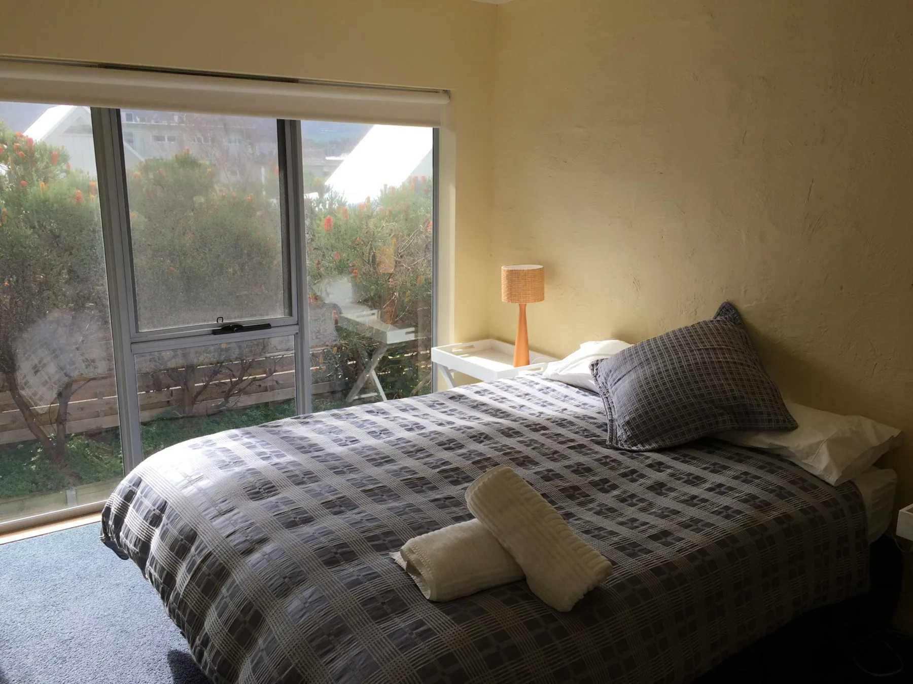 A bedroom with a bed beside a large sliding glass door.