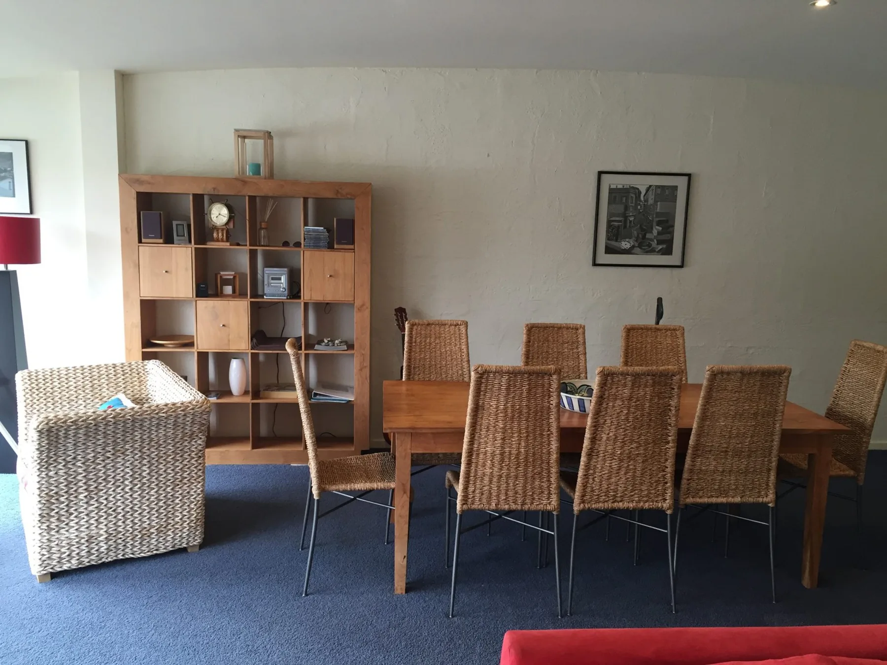 A dining area with a long wooden table and woven chairs.