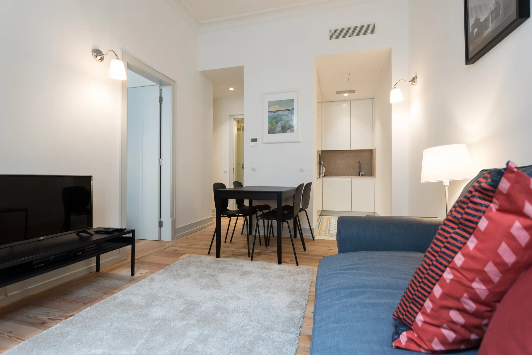 Living room with a dining table, television, and blue seating.