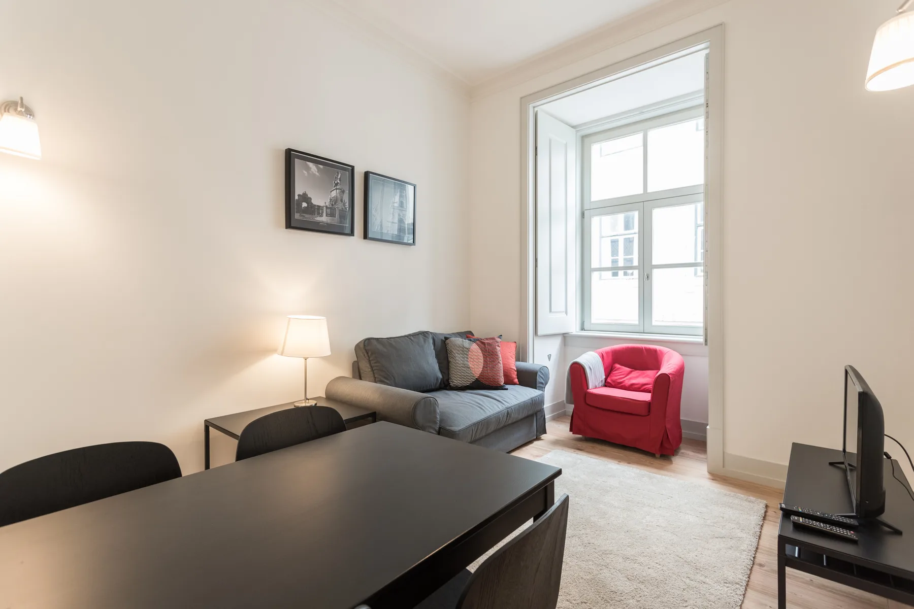 A living room with seating, a dining table, and a large window.