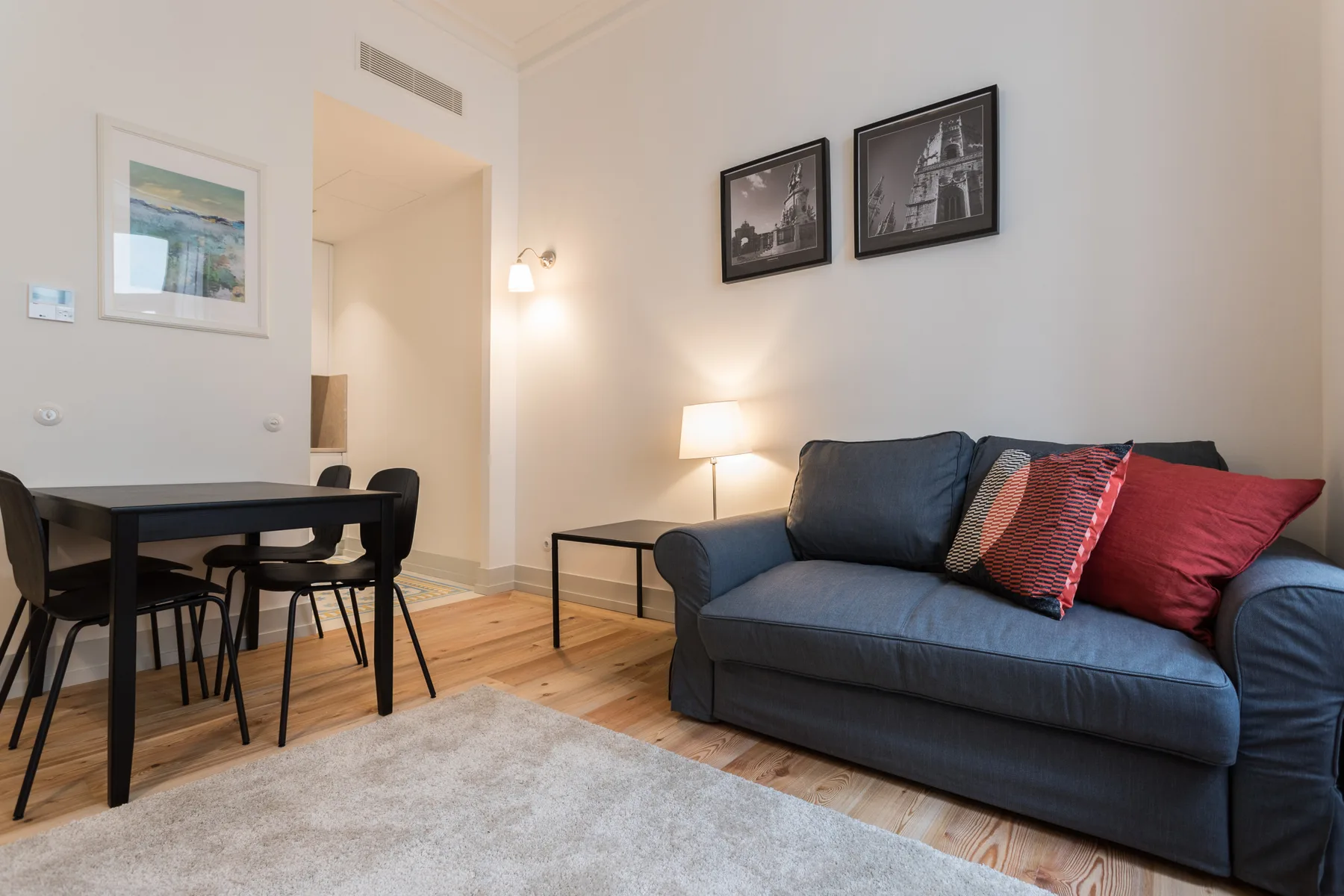 A bright living and dining area with a dark sofa and a table.
