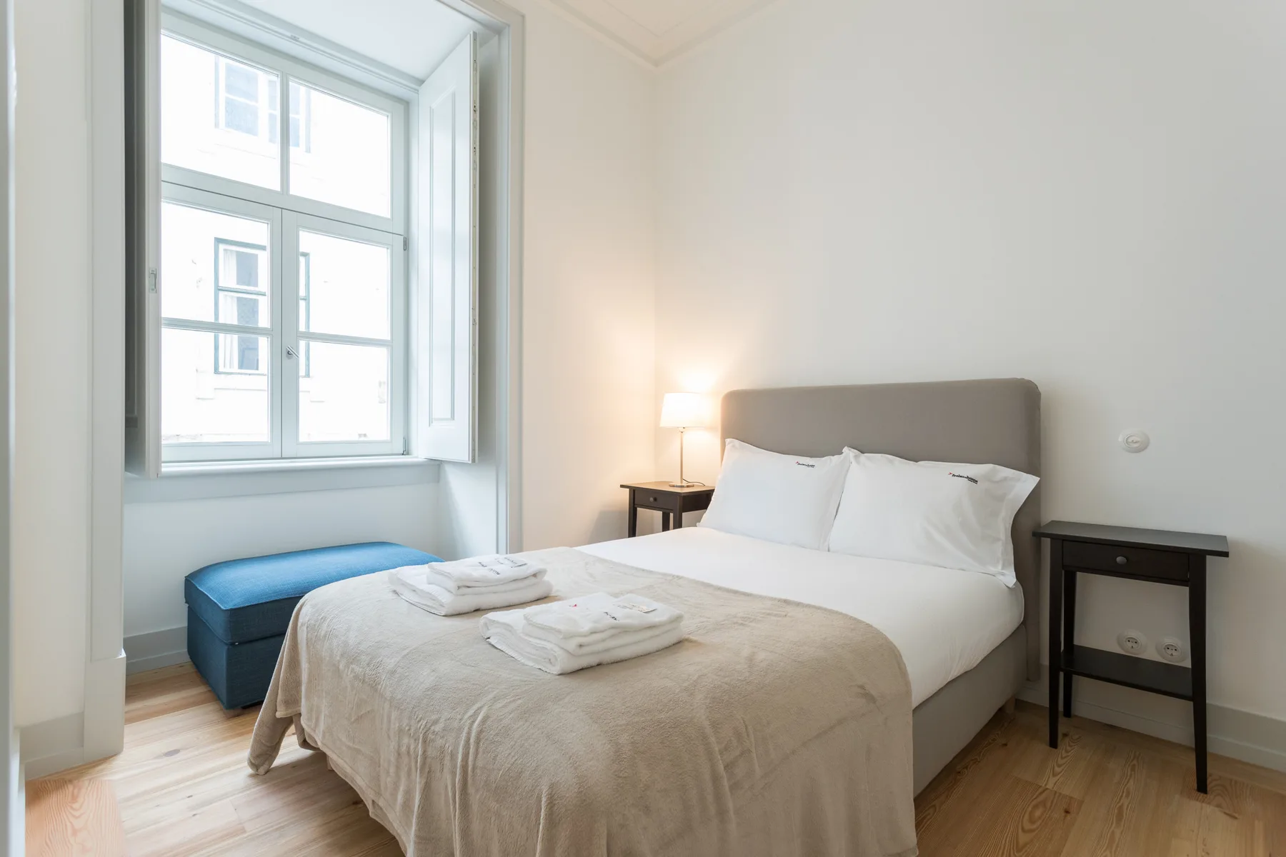 A bedroom with a neatly made bed and a large window.