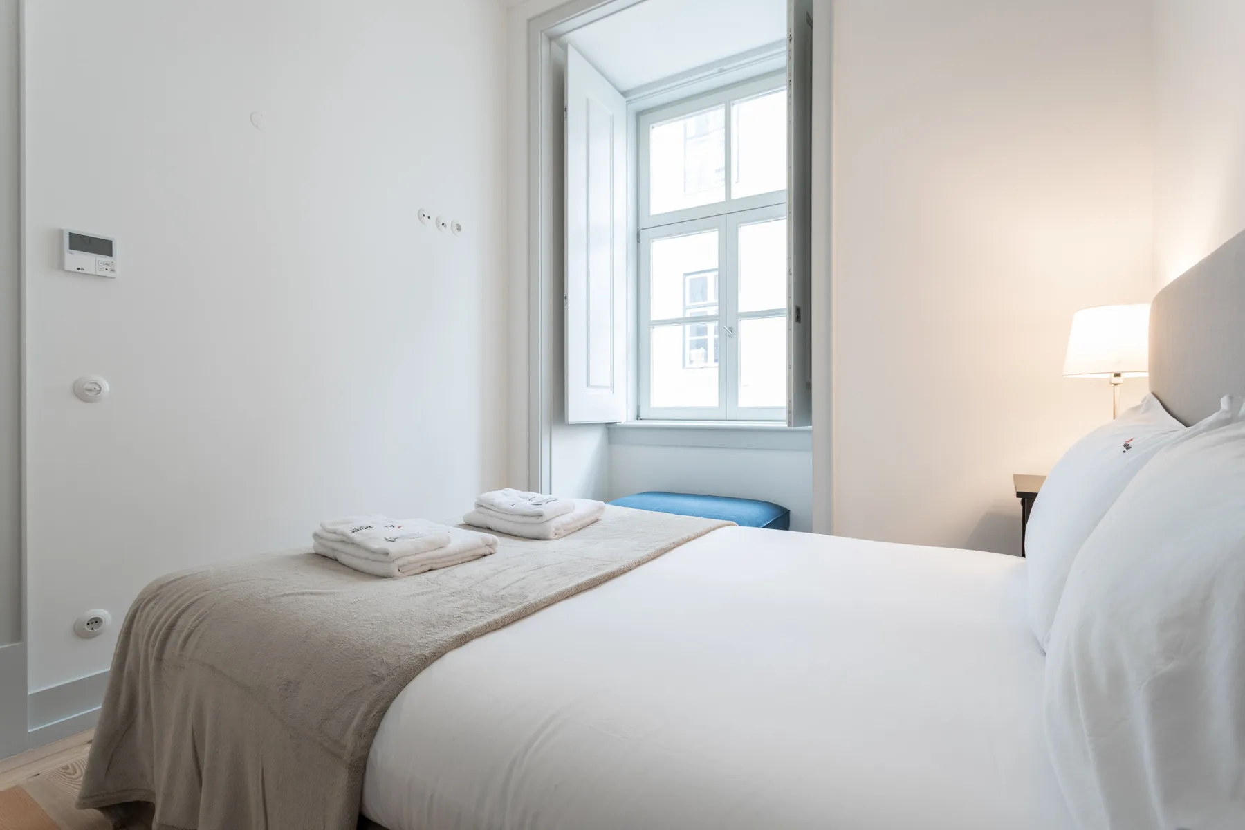 A bright bedroom with a large bed beside a tall window.