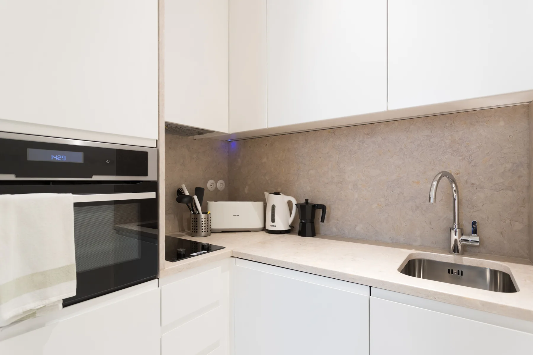 A modern kitchen with white cabinets, a countertop, and a sink.