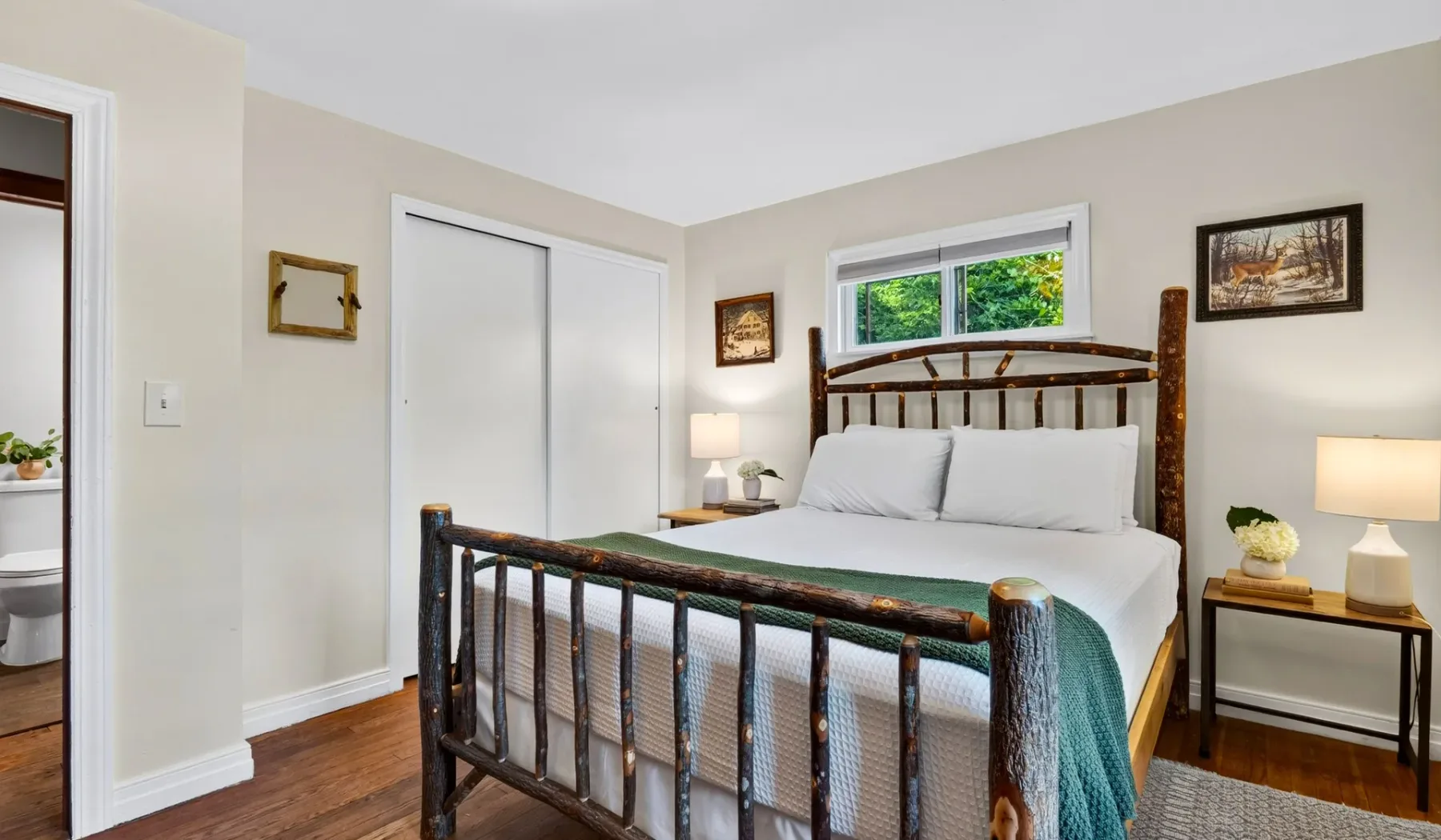 Un dormitorio con una cama, ropa de cama blanca y un armazón de madera.