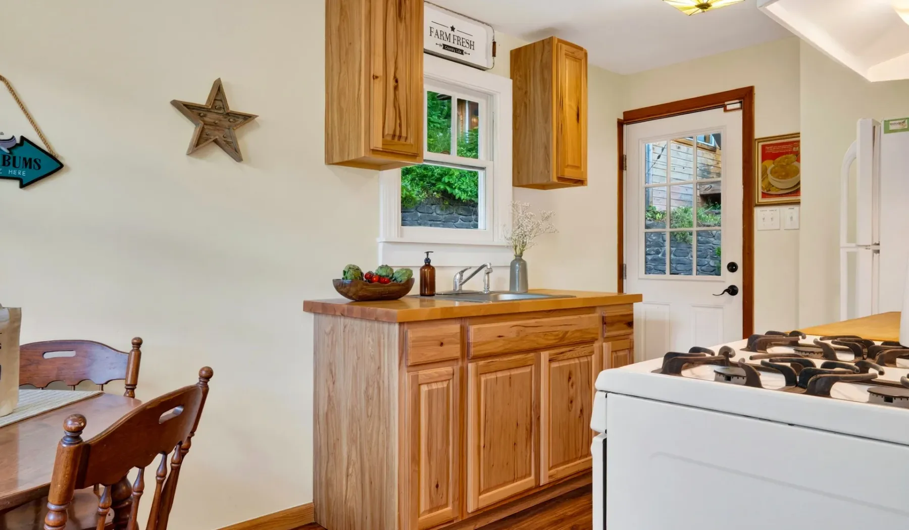 Una cocina con gabinetes de madera, un fregadero y una estufa junto a una puerta acristalada.