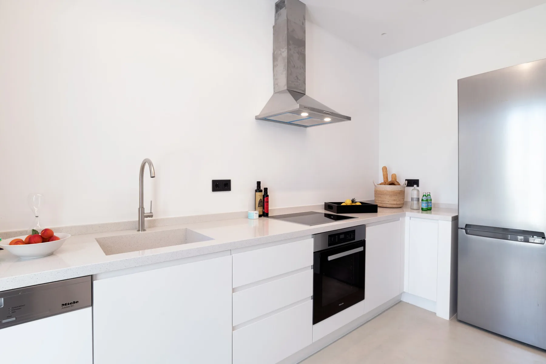 A bright modern kitchen with white cabinets and stainless steel appliances.