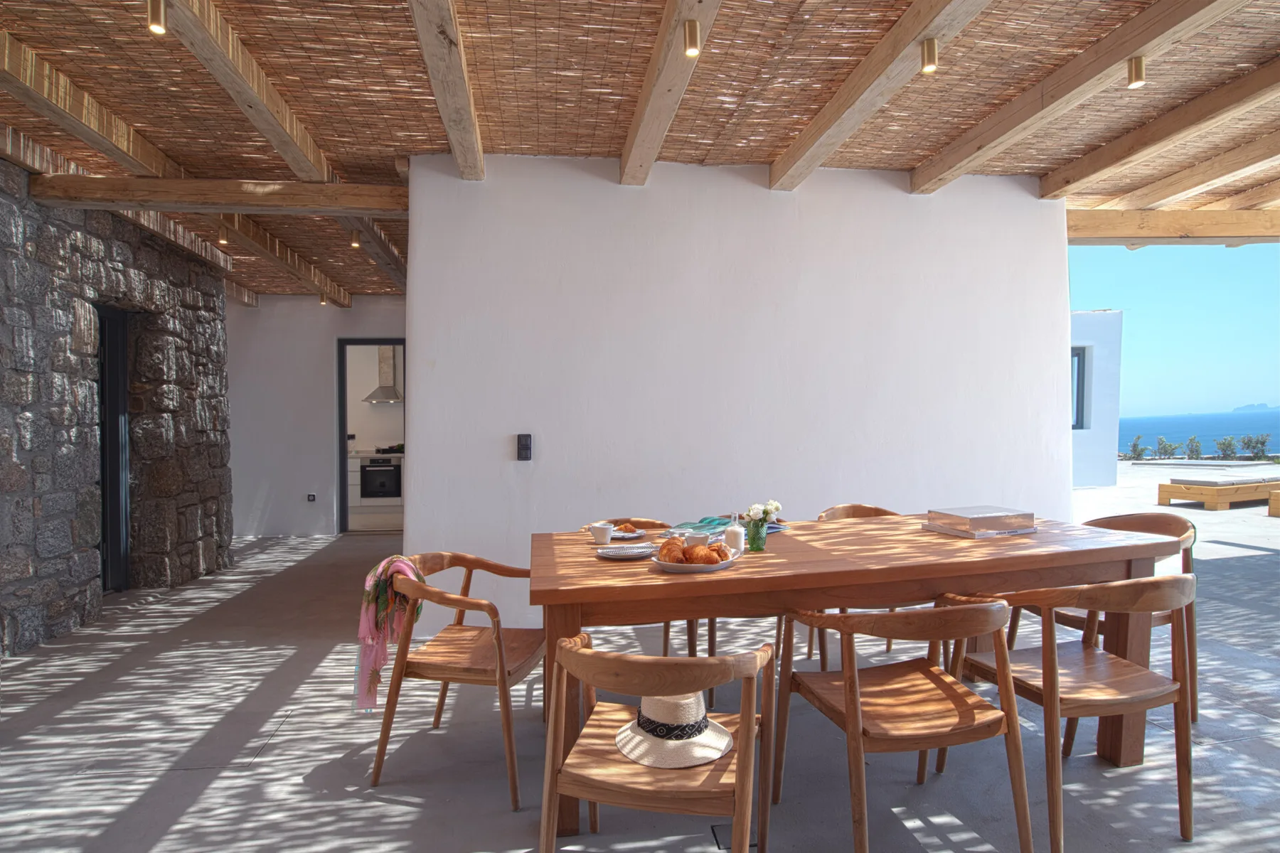 A shaded outdoor dining area with a wooden table and chairs.