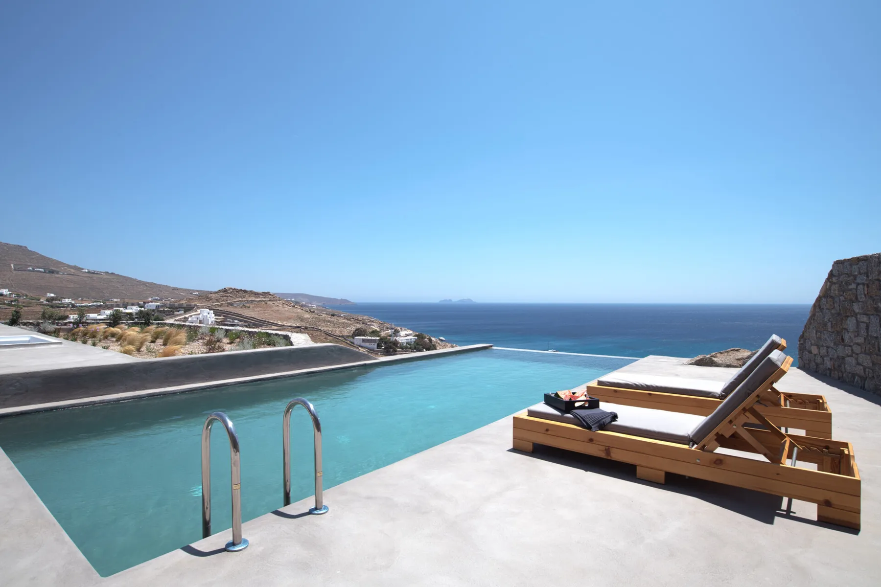 An infinity pool overlooks the sea, with sun loungers on the surrounding terrace.