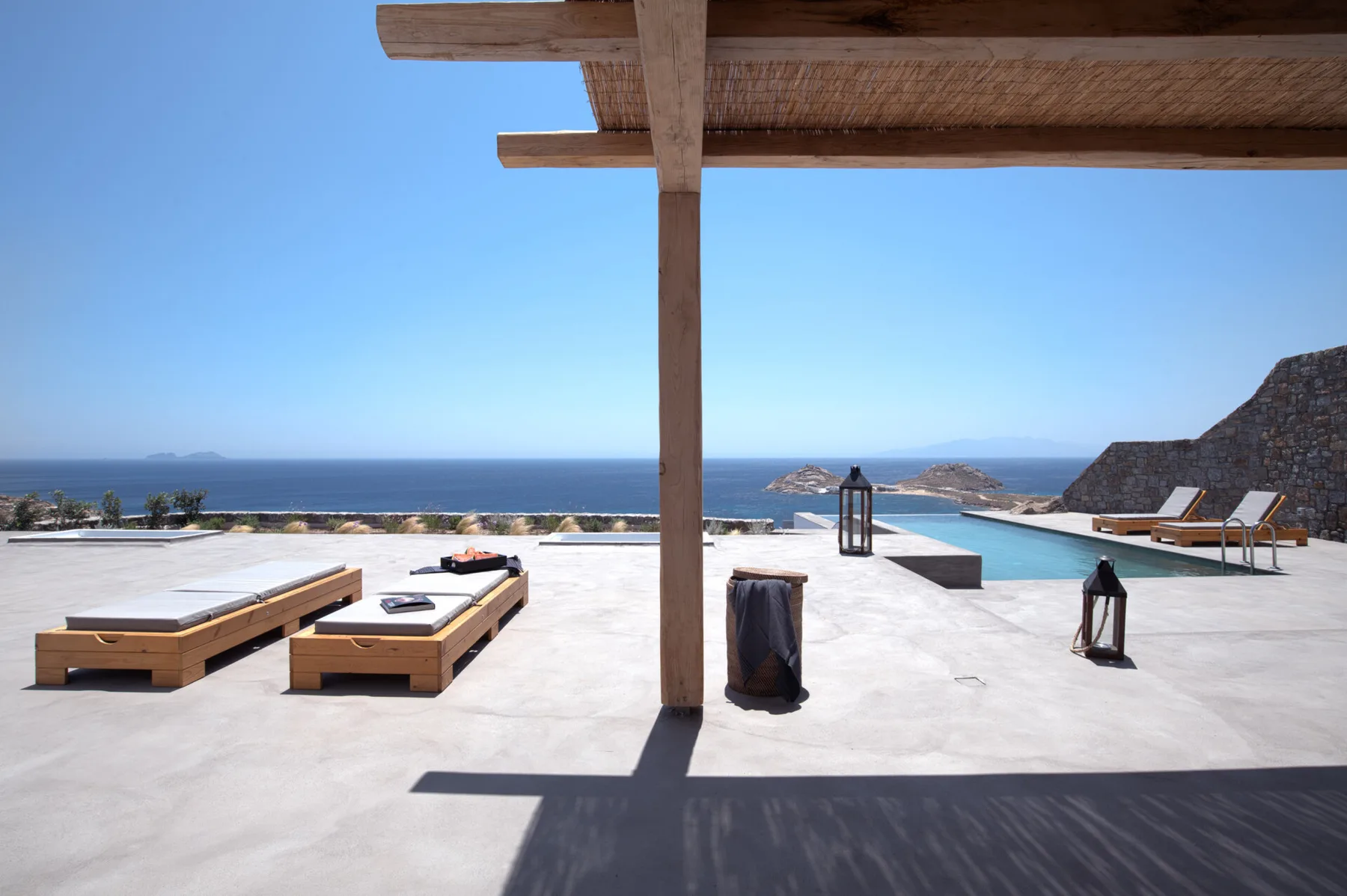 Outdoor pool terrace with lounge seating overlooking the sea.