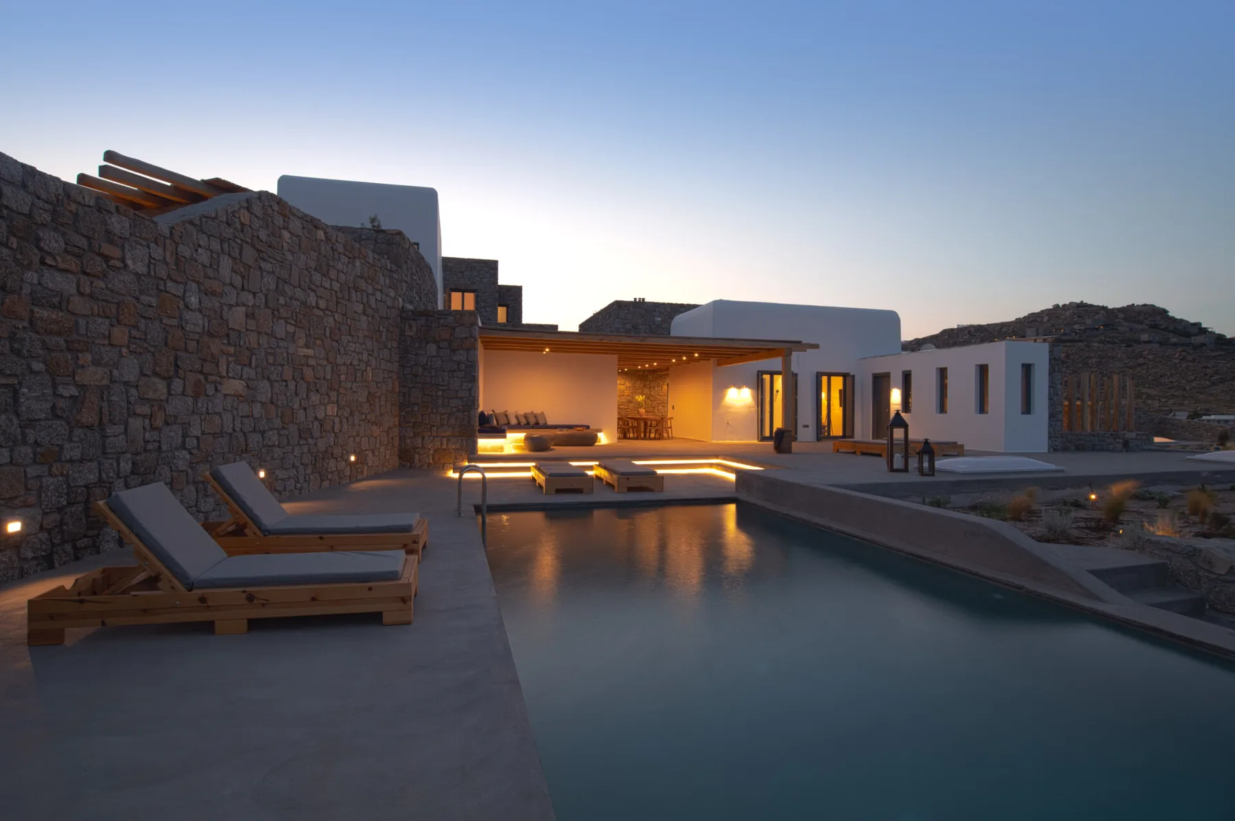 A modern villa courtyard with a swimming pool and outdoor seating at dusk.