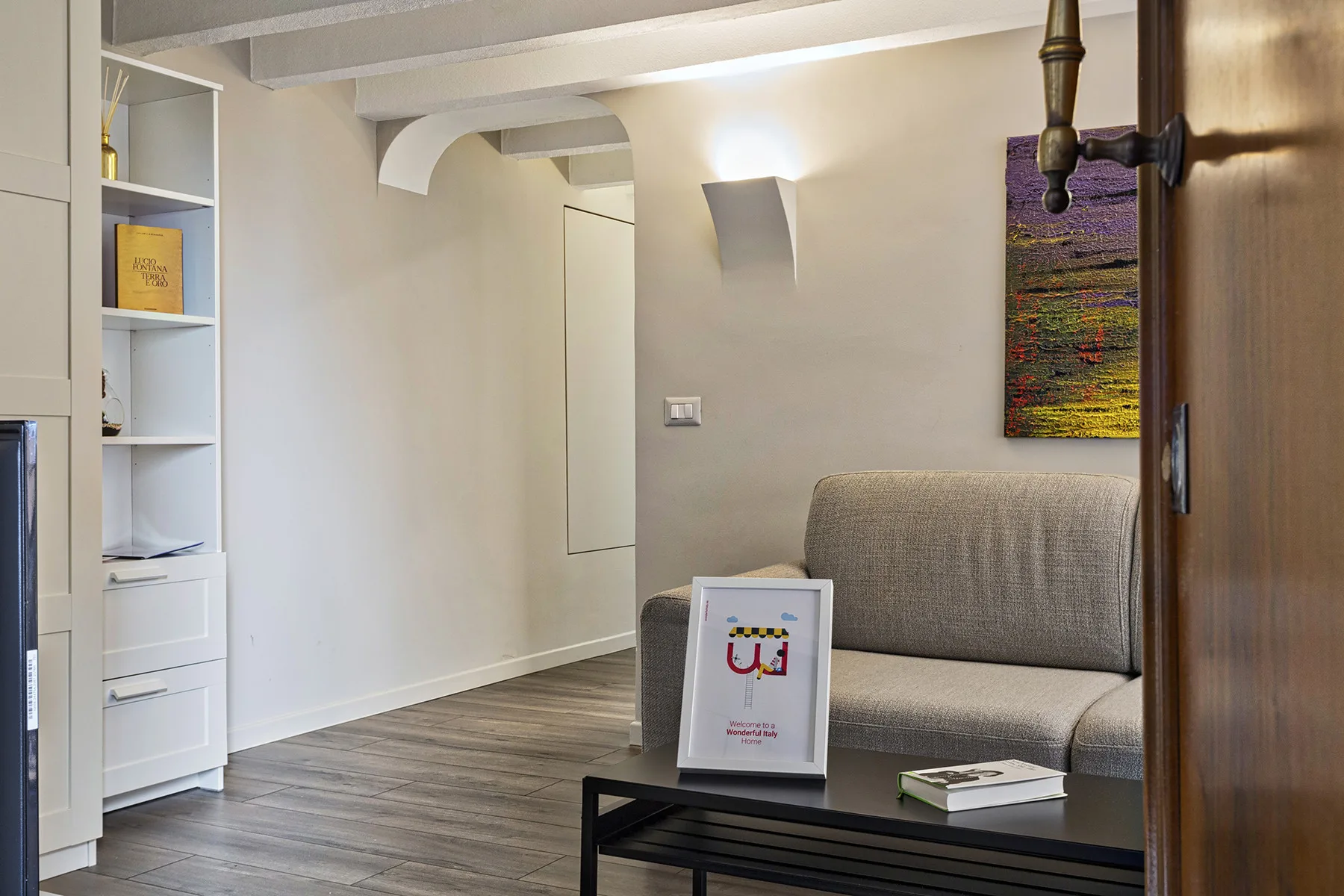 Una sala de estar con un sofá gris, estanterías empotradas y una mesa de centro.