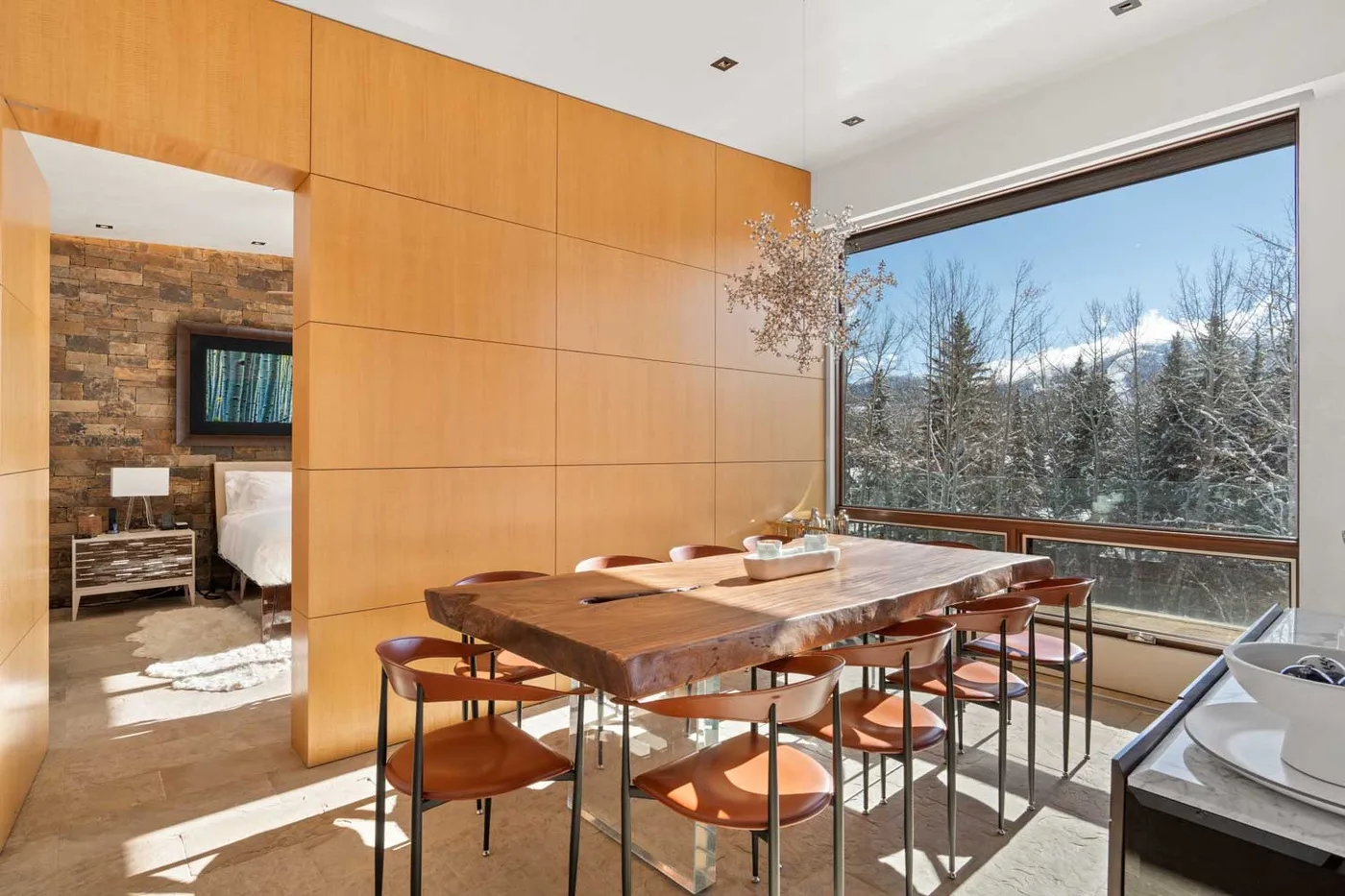 A dining area with a wooden table beside a large window overlooking trees.