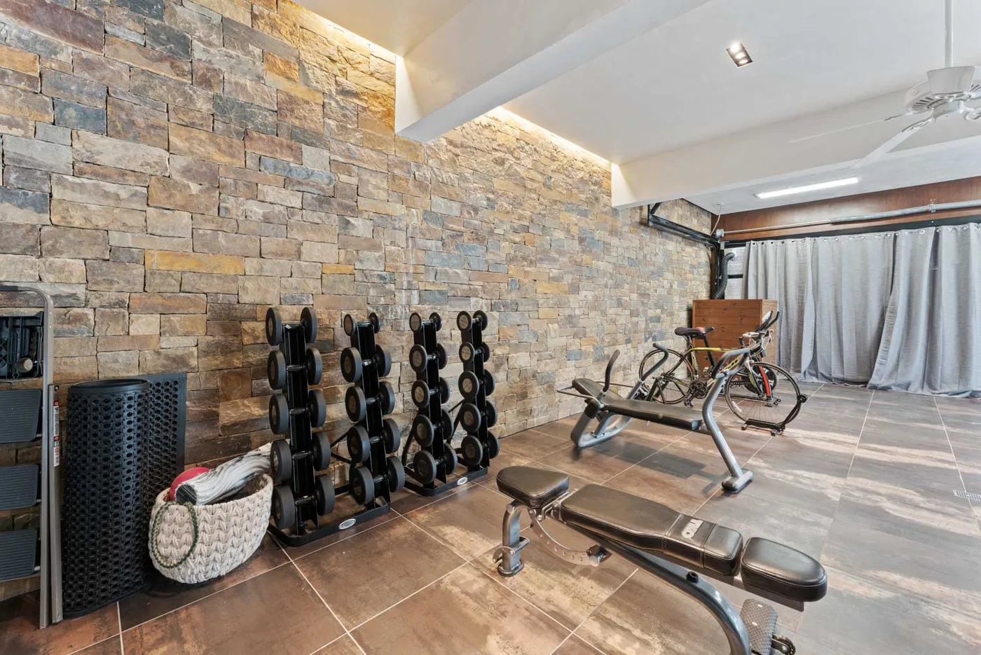A home gym with weight racks, exercise bikes, and a workout bench.
