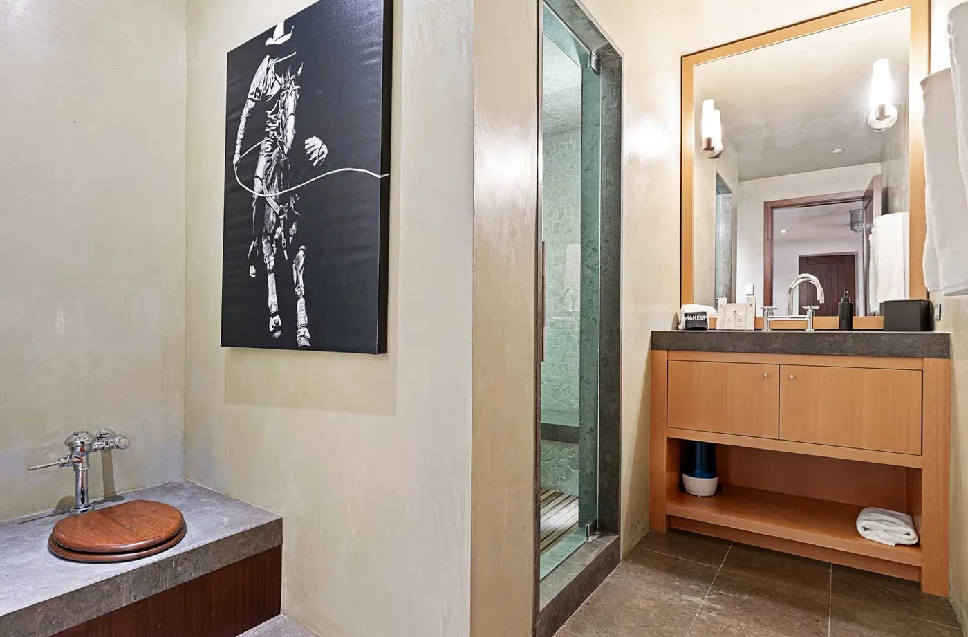 A bathroom with a wooden vanity, sink, and glass shower.