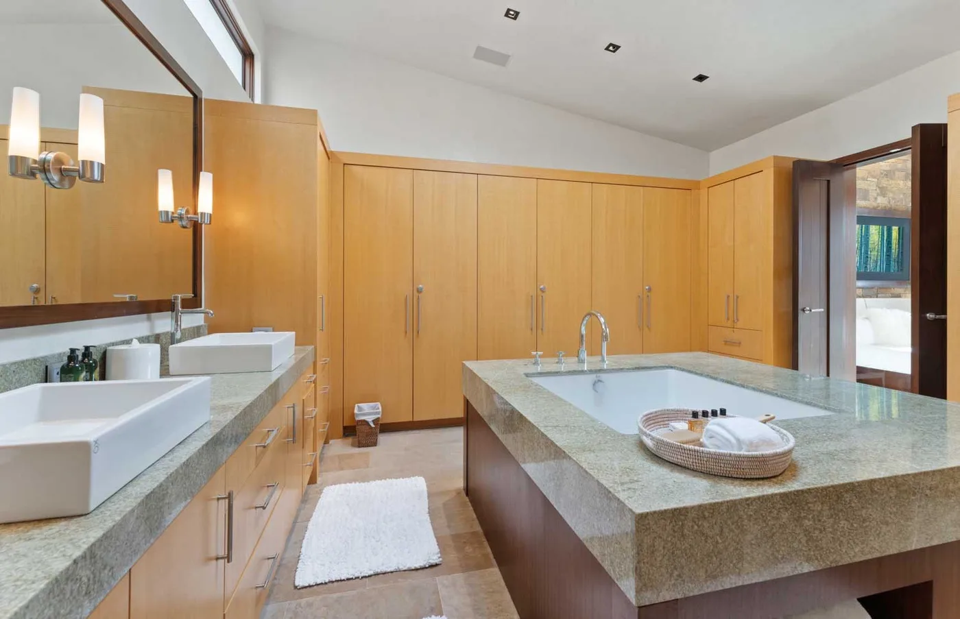 A spacious bathroom with a central soaking tub, double sinks, and wood cabinetry.
