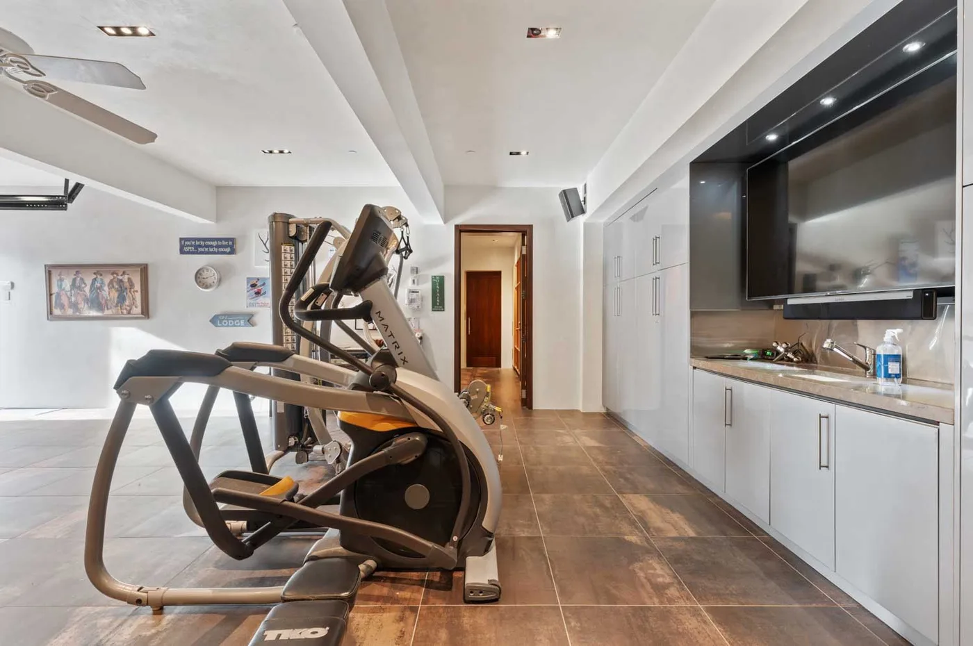 A home gym with exercise machines and built-in cabinets along the wall.