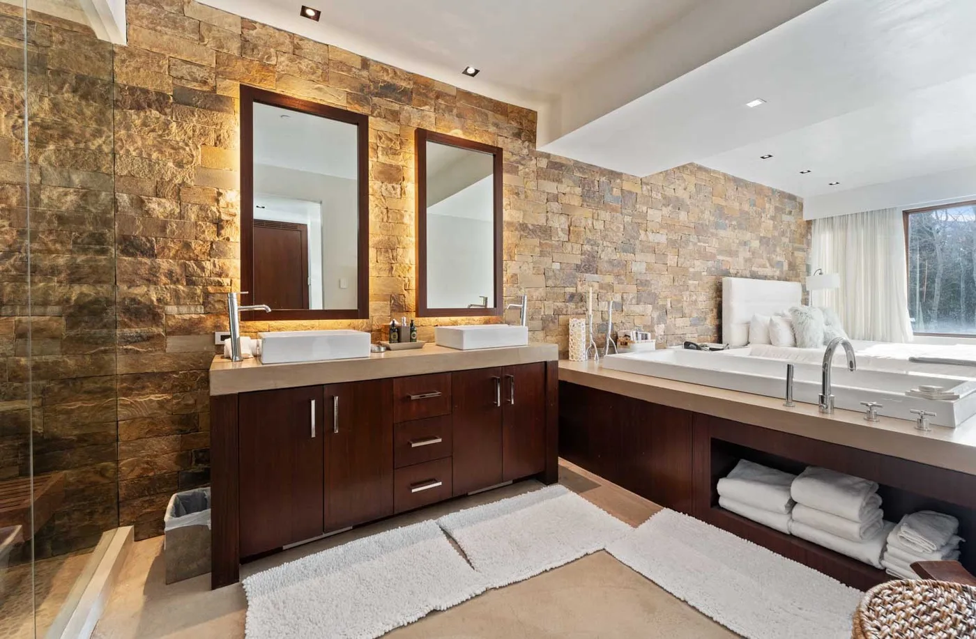 A spacious bathroom with two sinks and a bathtub beside a large window.