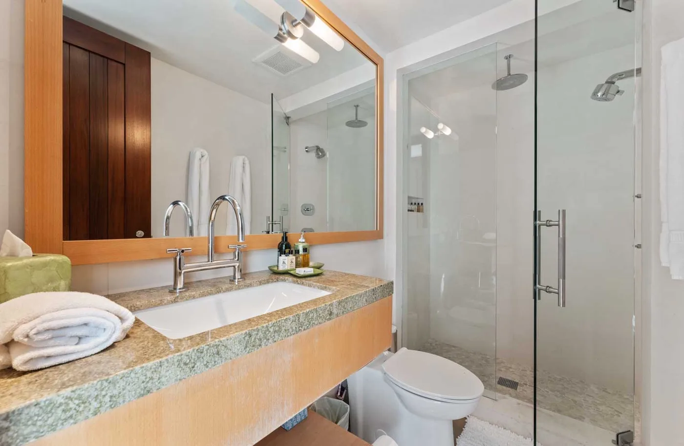 A bathroom with a long vanity, sink, and glass-enclosed shower.