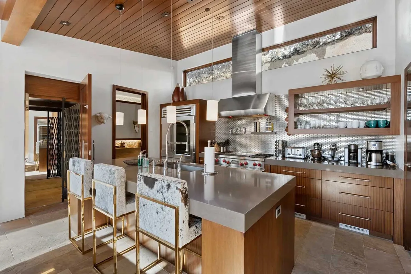 A modern kitchen with a central island, bar seating, and wood cabinetry.