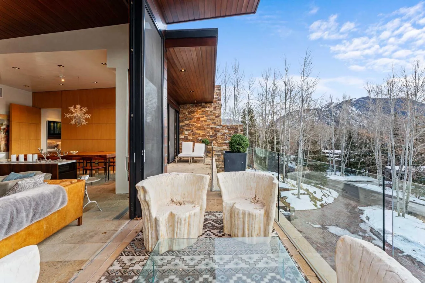 A glass-enclosed terrace with seating overlooks a snowy landscape.