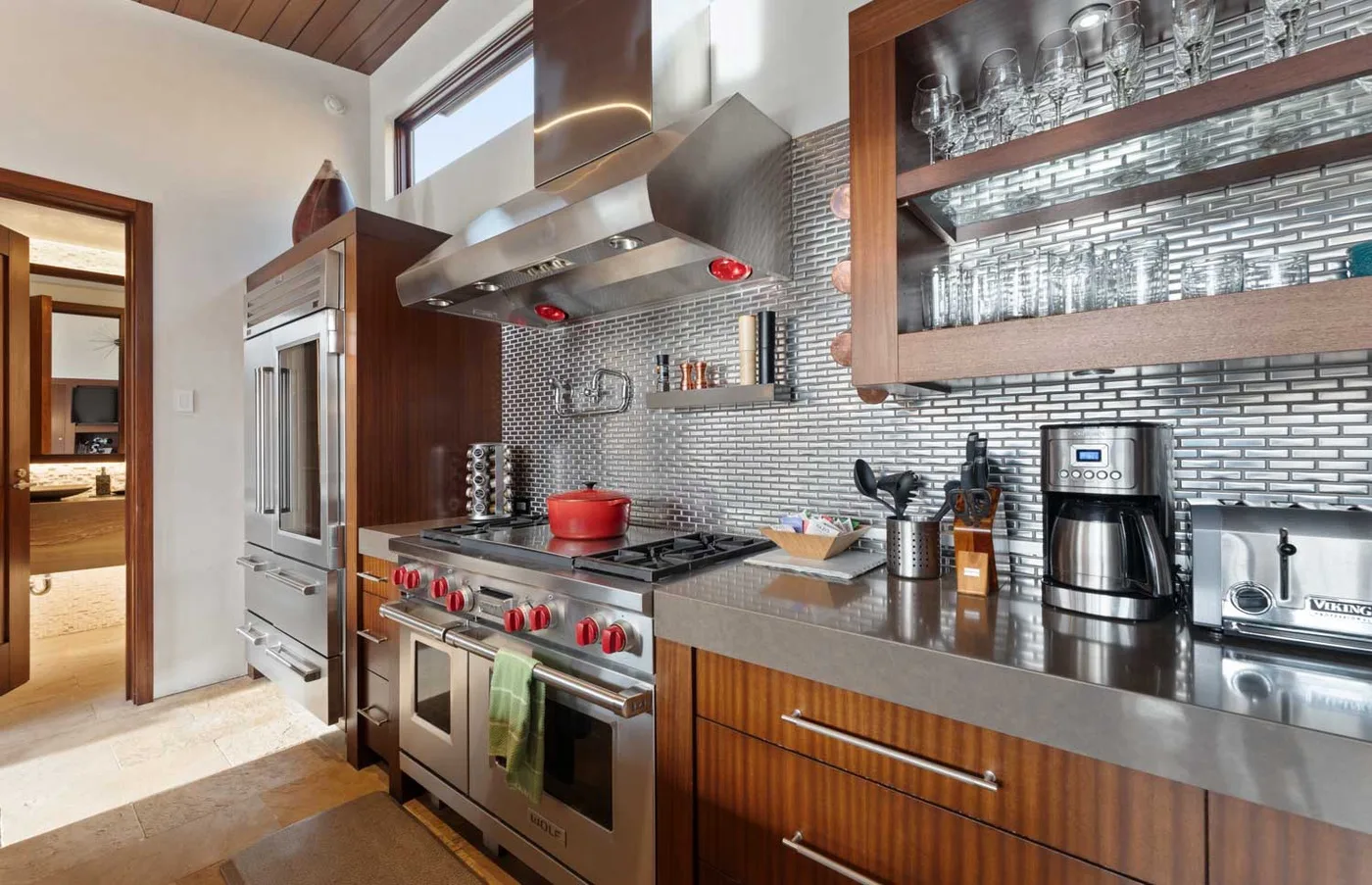 A modern kitchen with a stainless steel range and open shelving.