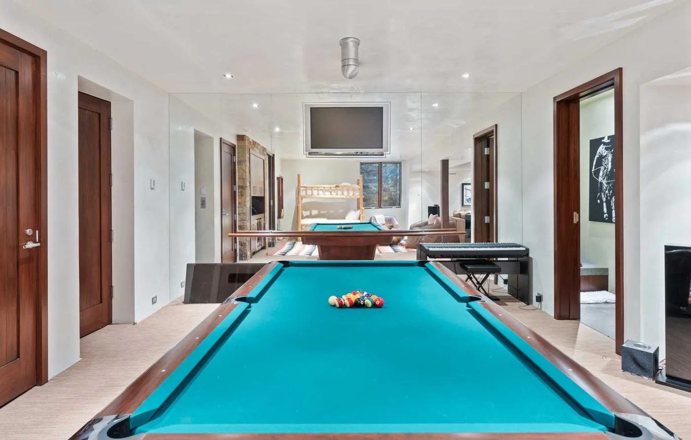 A billiards room with a teal pool table and seating.