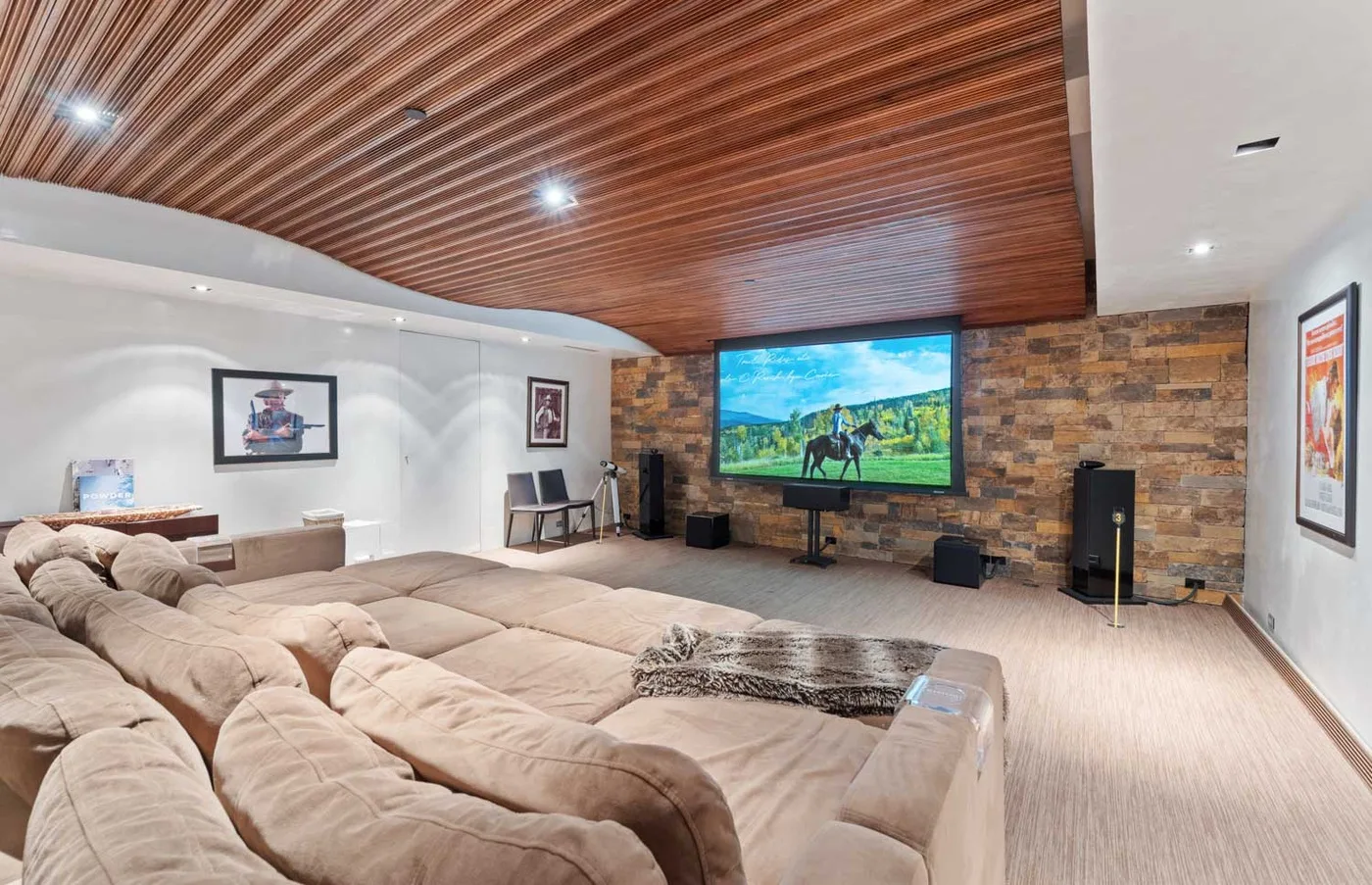 A spacious media room features sectional seating facing a large television.