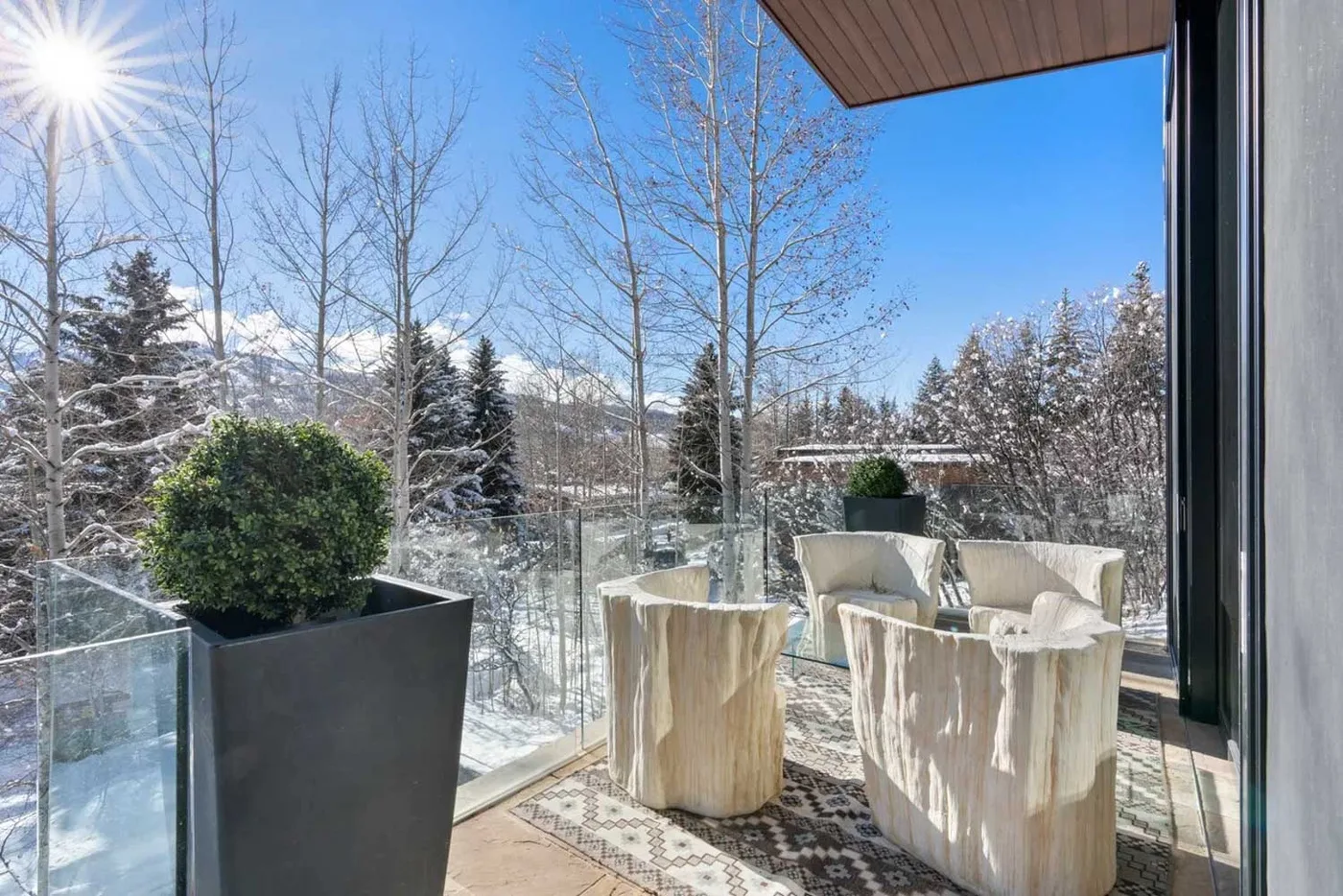 A sunny outdoor seating area overlooks a snowy landscape.