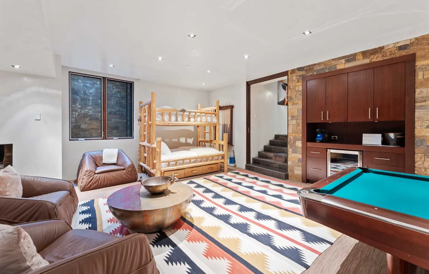 A colorful recreation room with a pool table, seating, and bunk beds.