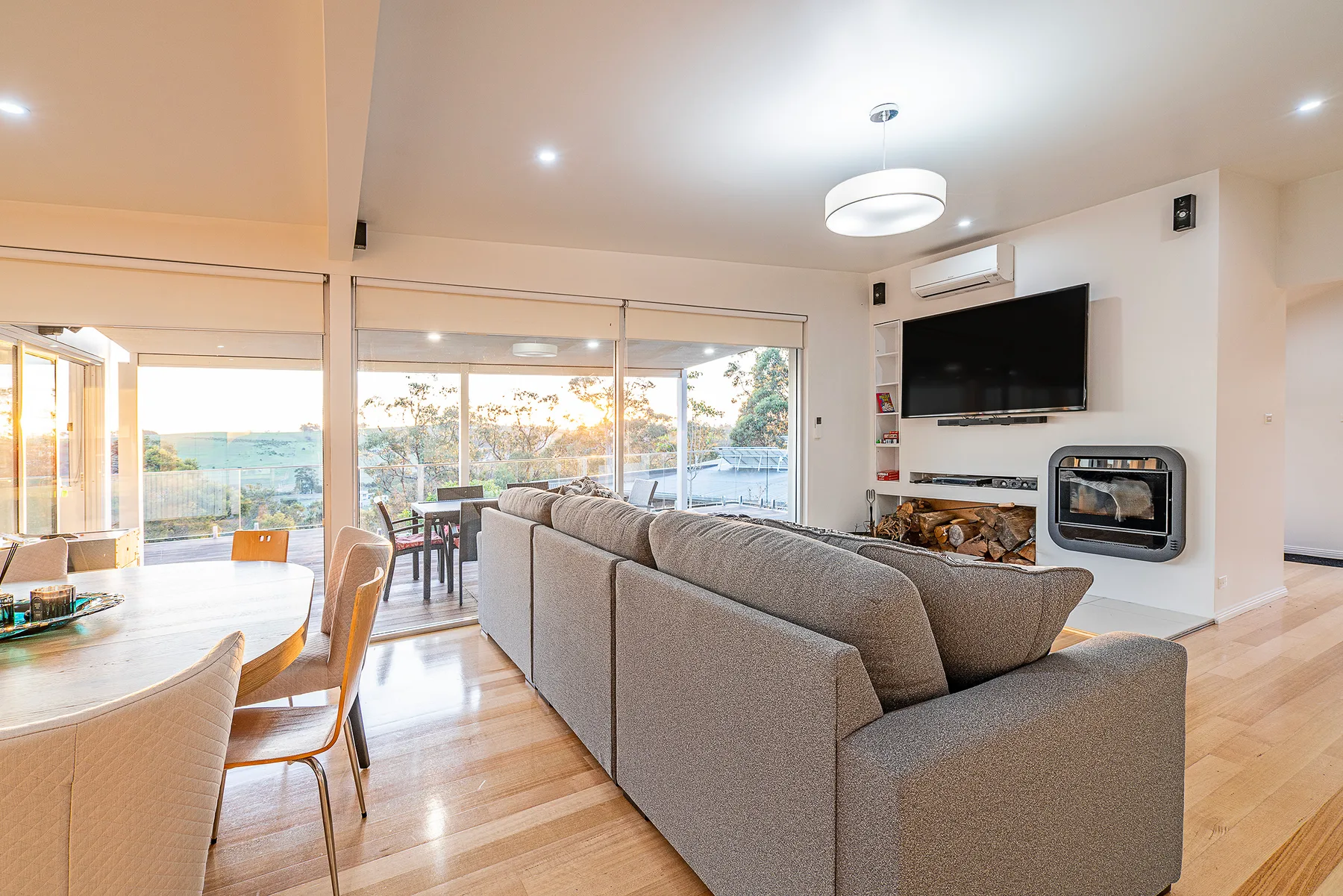 A living room with seating, a television, and broad windows overlooking the water.