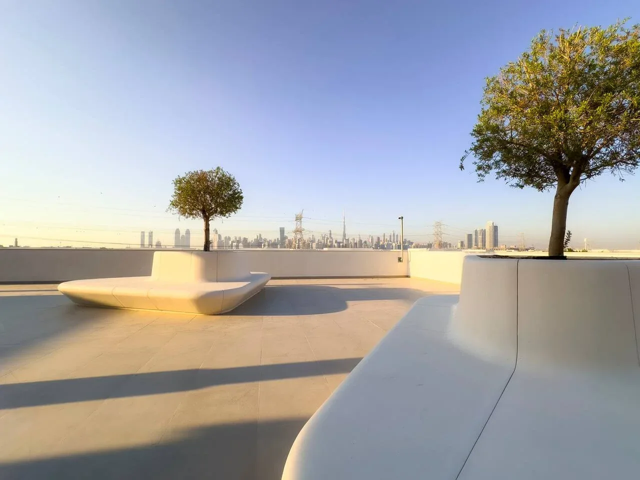 Una terraza abierta en la azotea, con asientos integrados y árboles frente a la ciudad.