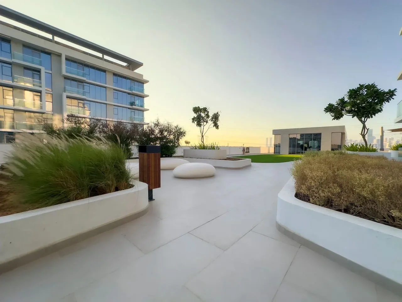 Una terraza exterior pavimentada con jardineras y edificios modernos.