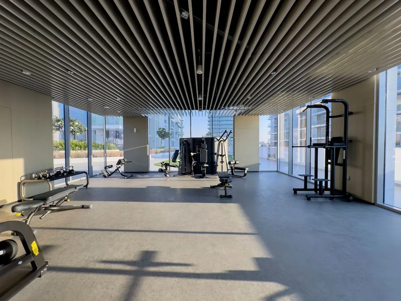 Una sala de ejercicio con equipos de entrenamiento y grandes ventanas.